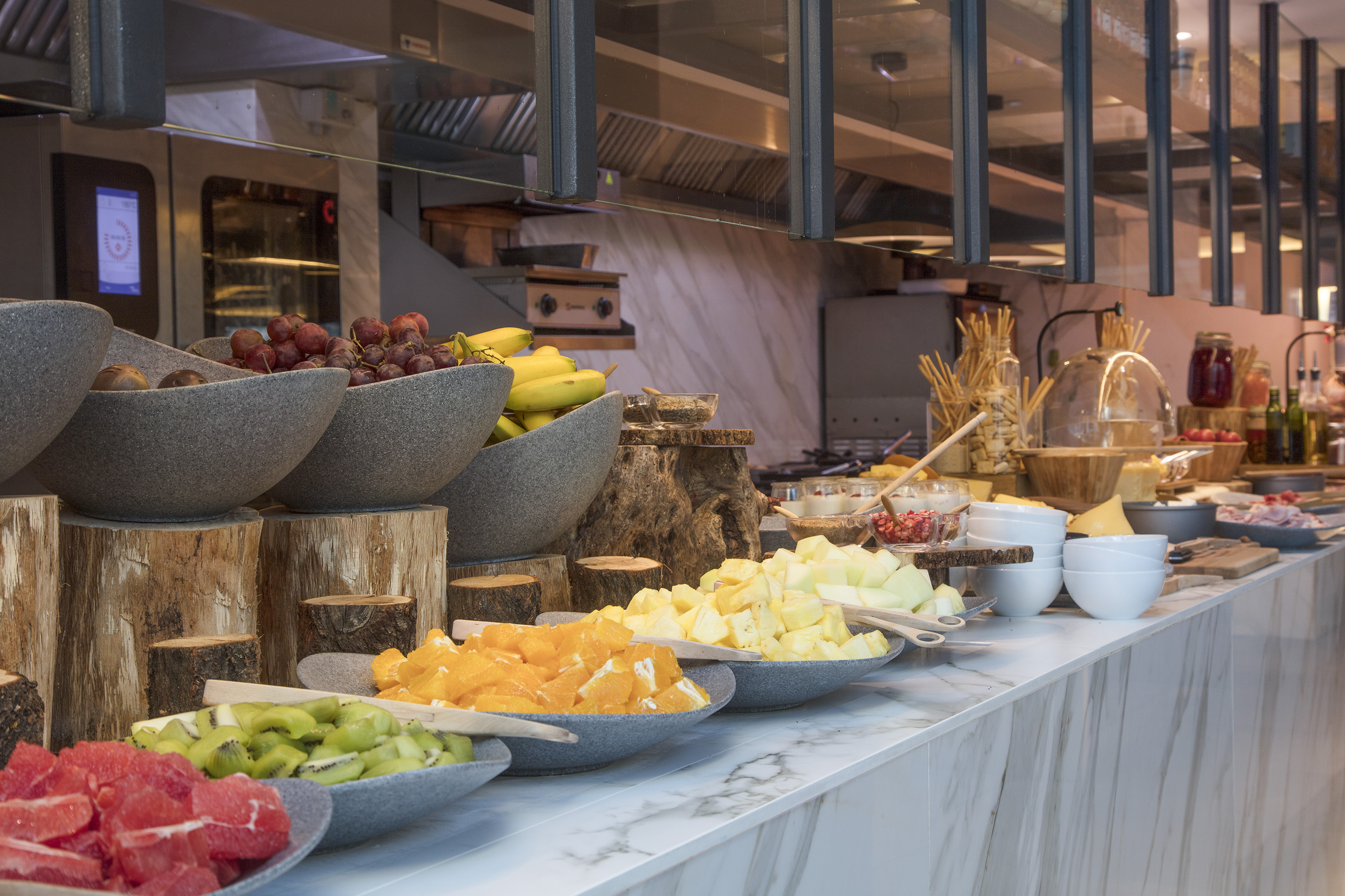 Hotel breakfast buffet with fresh grapes, bananas, and sliced fruits.