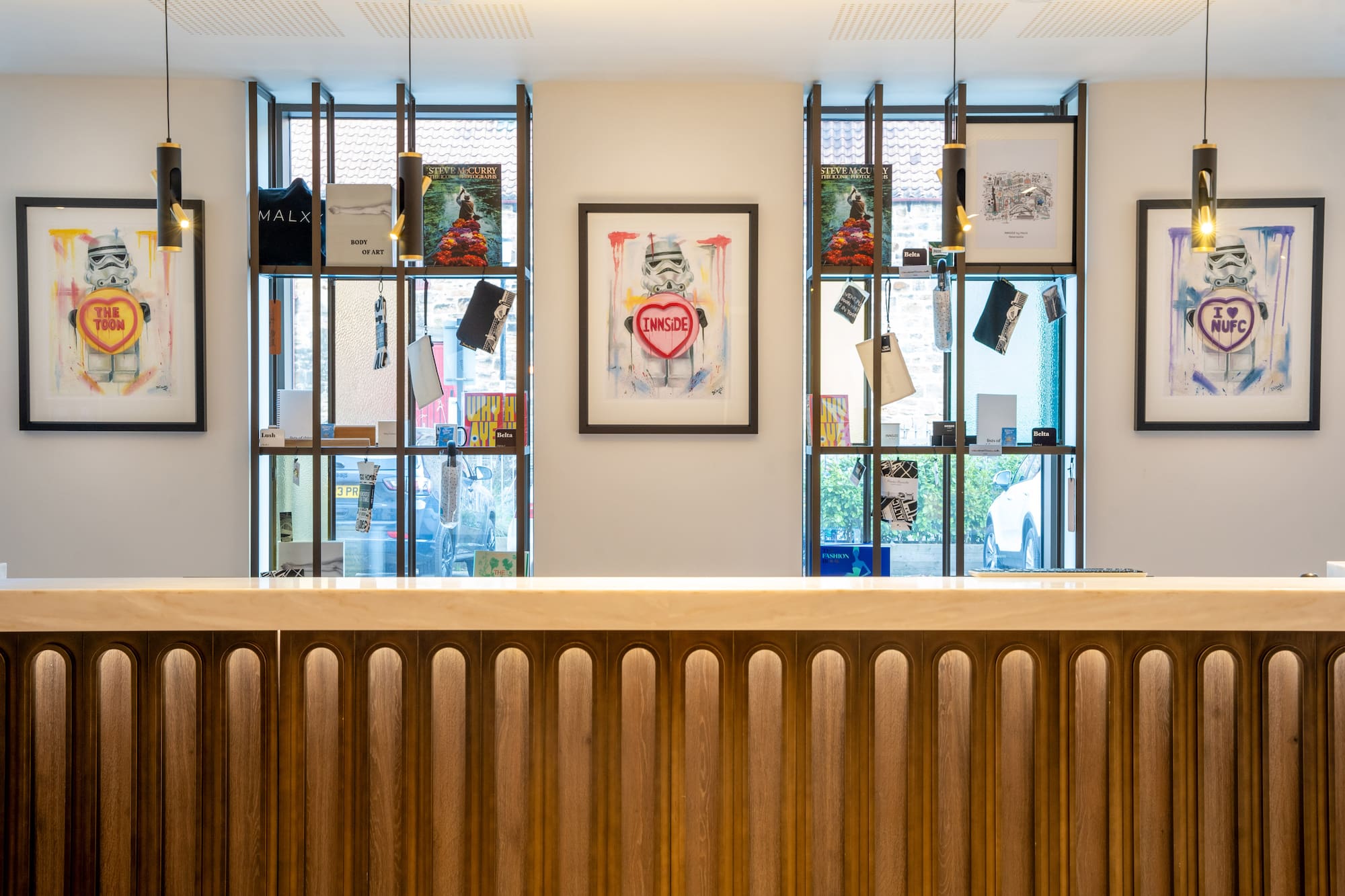 INNSIDE hotel reception: wooden desk, Stormtrooper art, modern display shelves.
