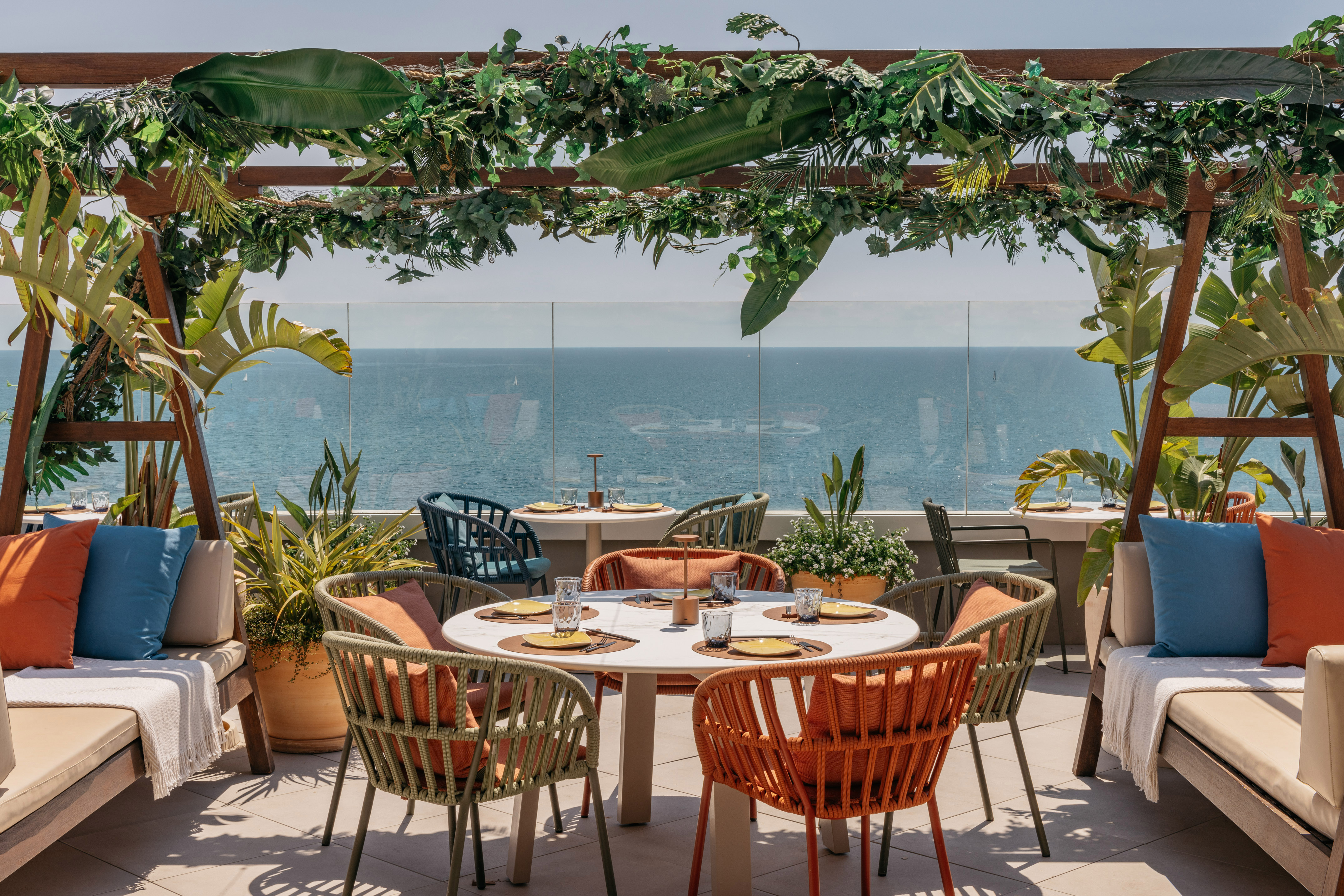 Beachfront rooftop dining with tropical pergola and ocean views.