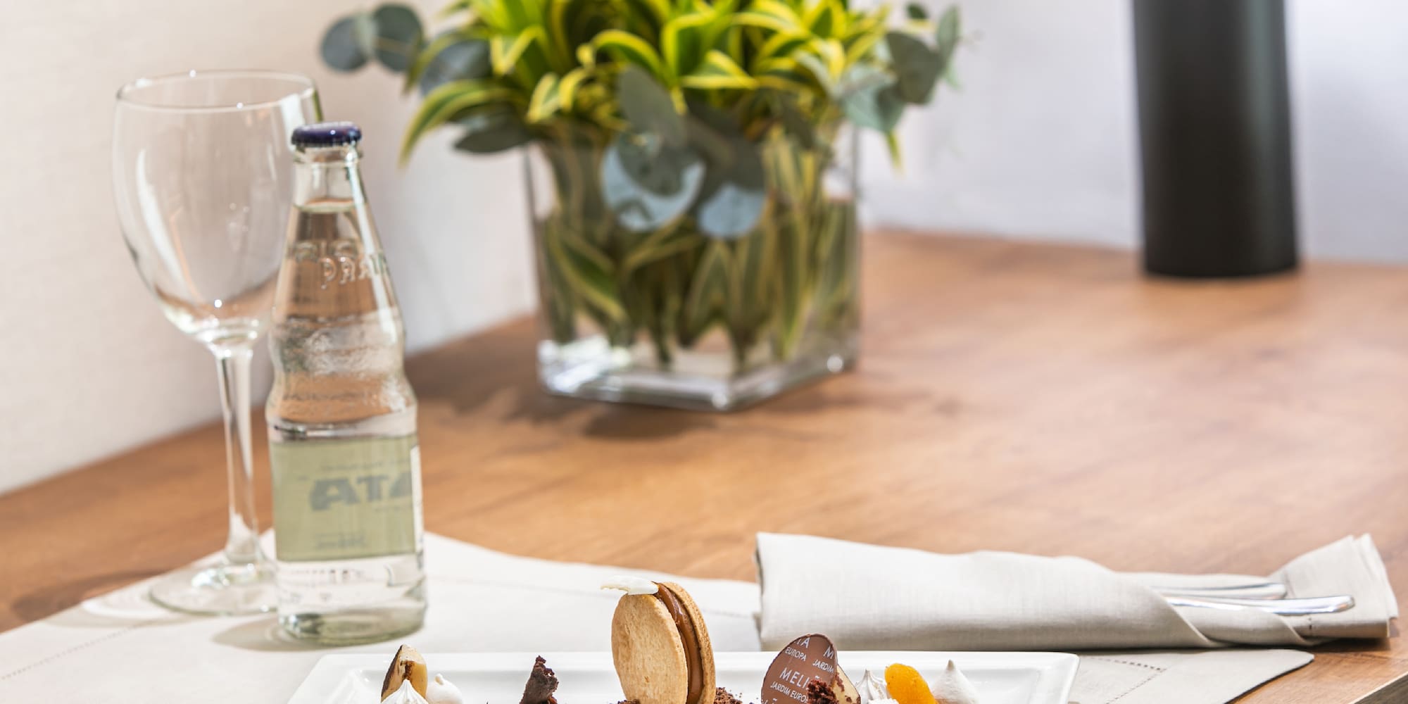 Gourmet dessert with biscuit, chocolate, meringue, and drink on wooden table.