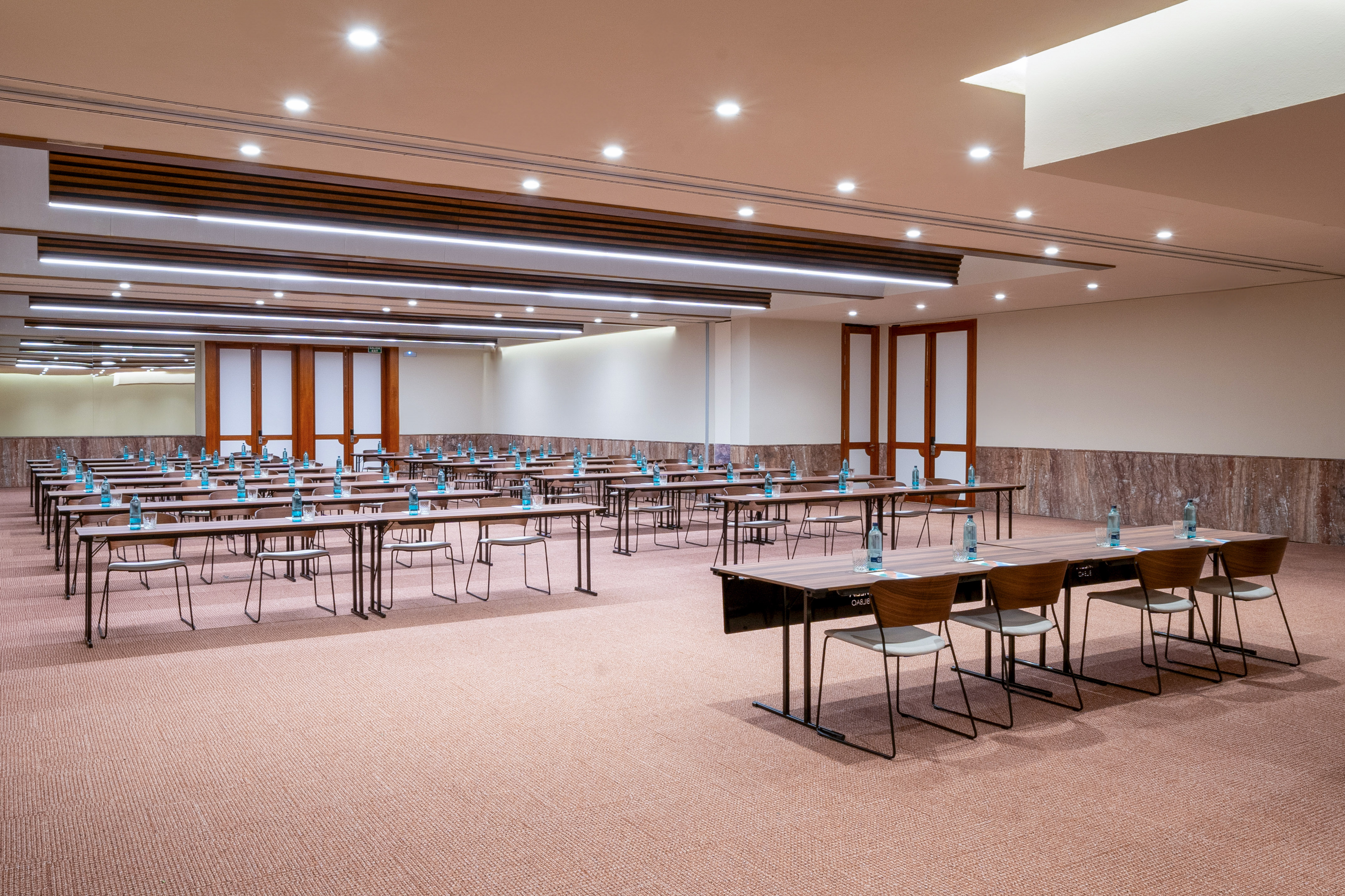 Empty conference room with classroom setup, tables, chairs, and water bottles.