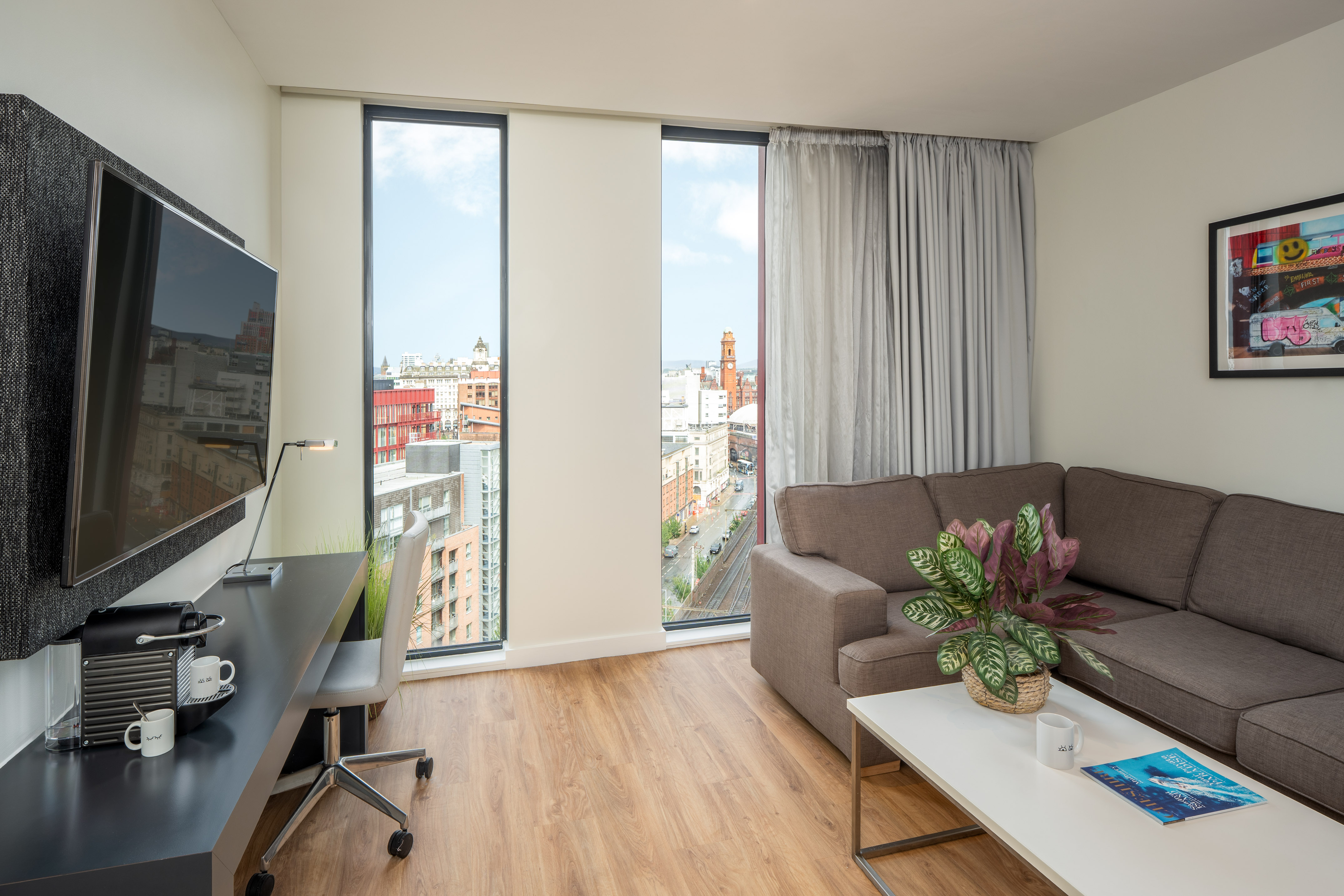 Modern apartment living room with city view, sofa, and workspace.