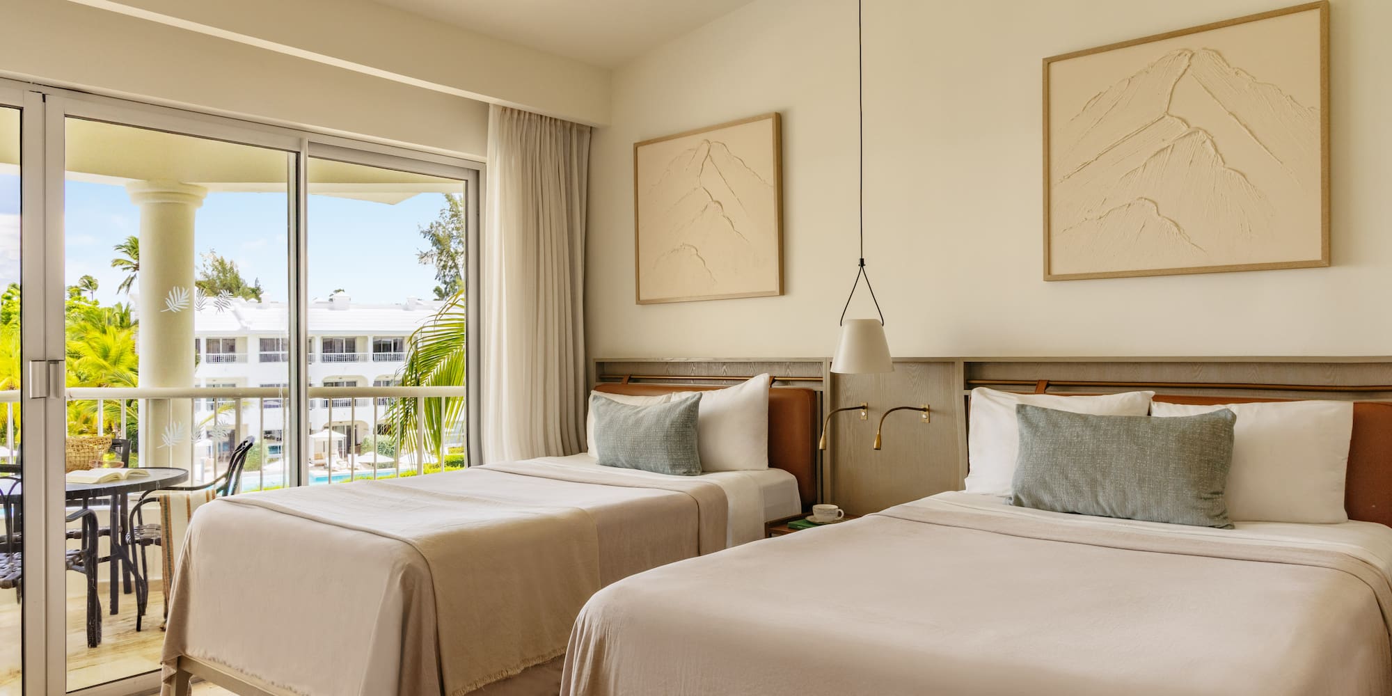 Modern resort room with twin beds, balcony, and tropical palm tree view.