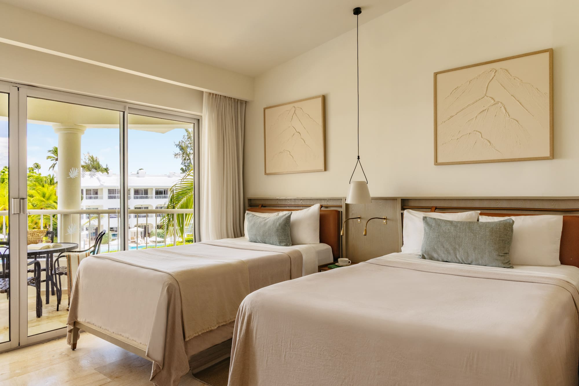 Modern resort room with twin beds, balcony, and tropical palm tree view.