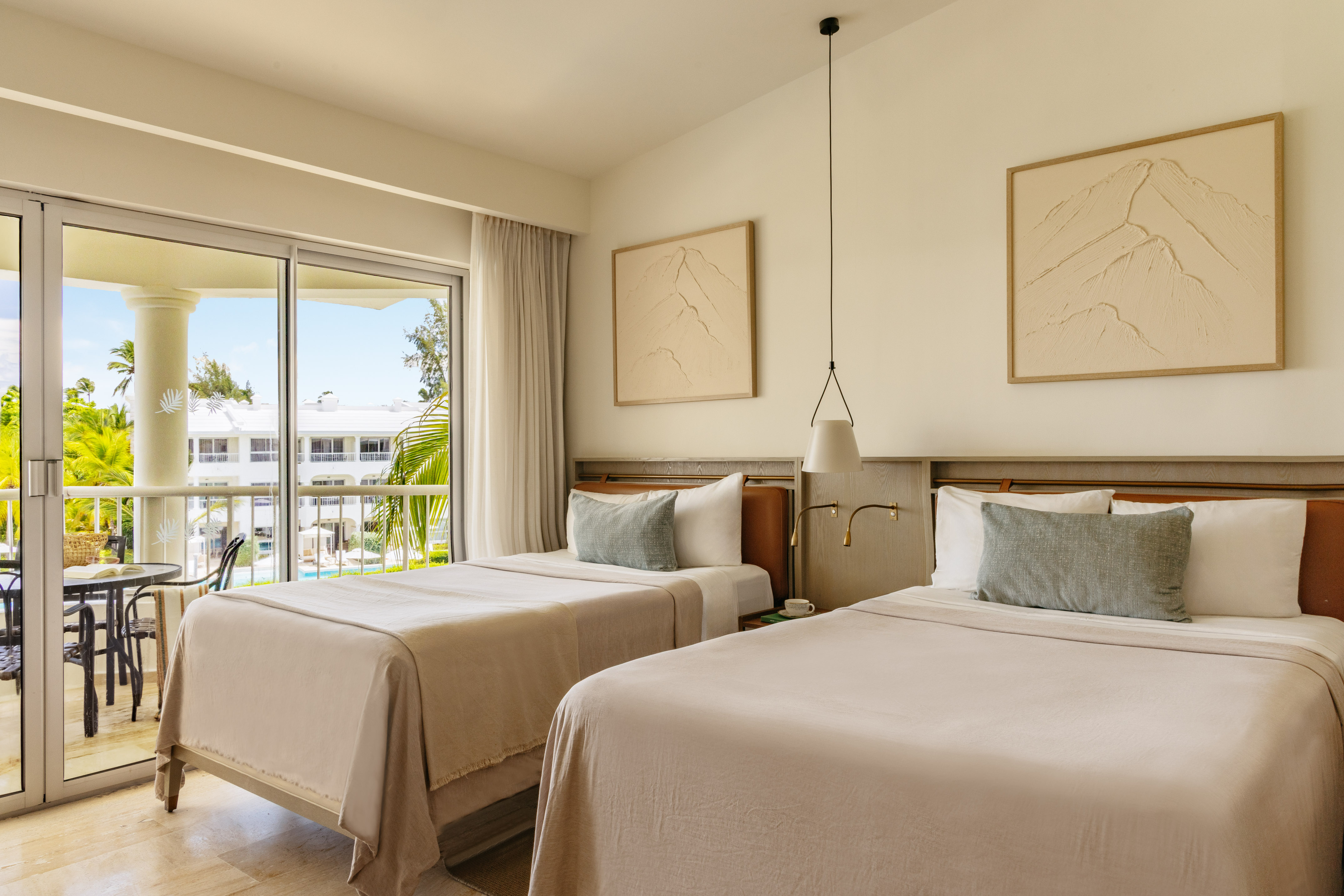 Modern resort room with twin beds, balcony, and tropical palm tree view.