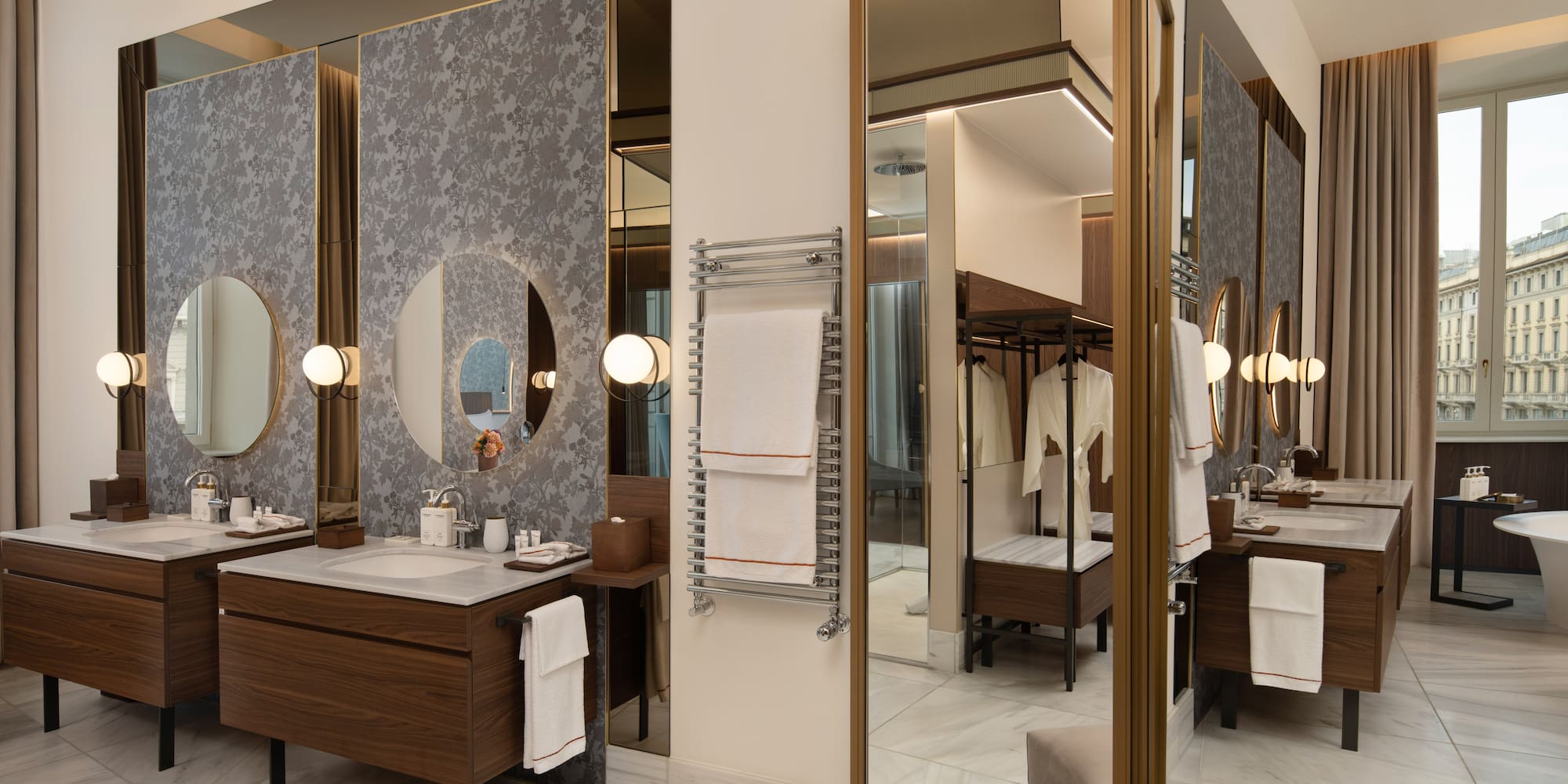 Luxury hotel bathroom with double vanity, round mirrors, marble, towel warmer.