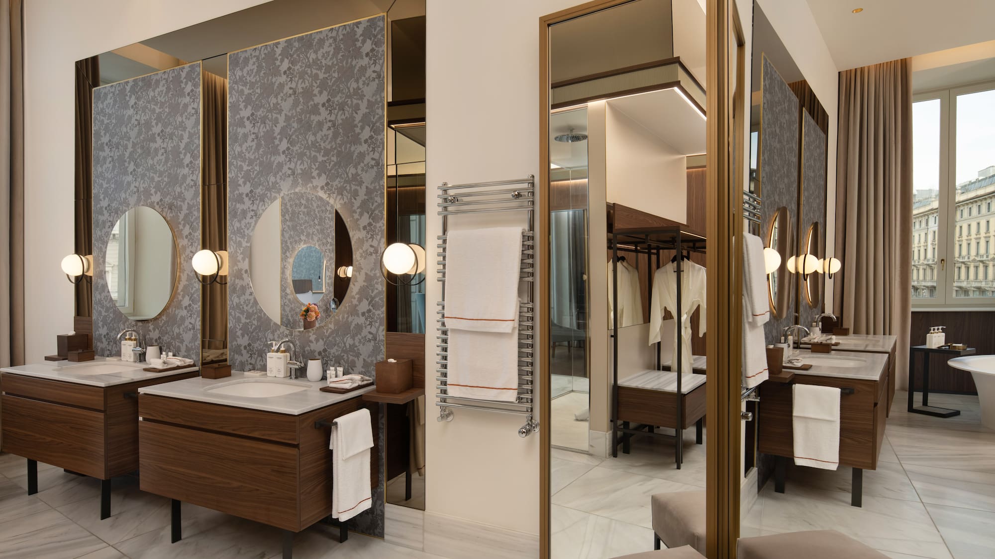 Luxury hotel bathroom with double vanity, round mirrors, marble, towel warmer.