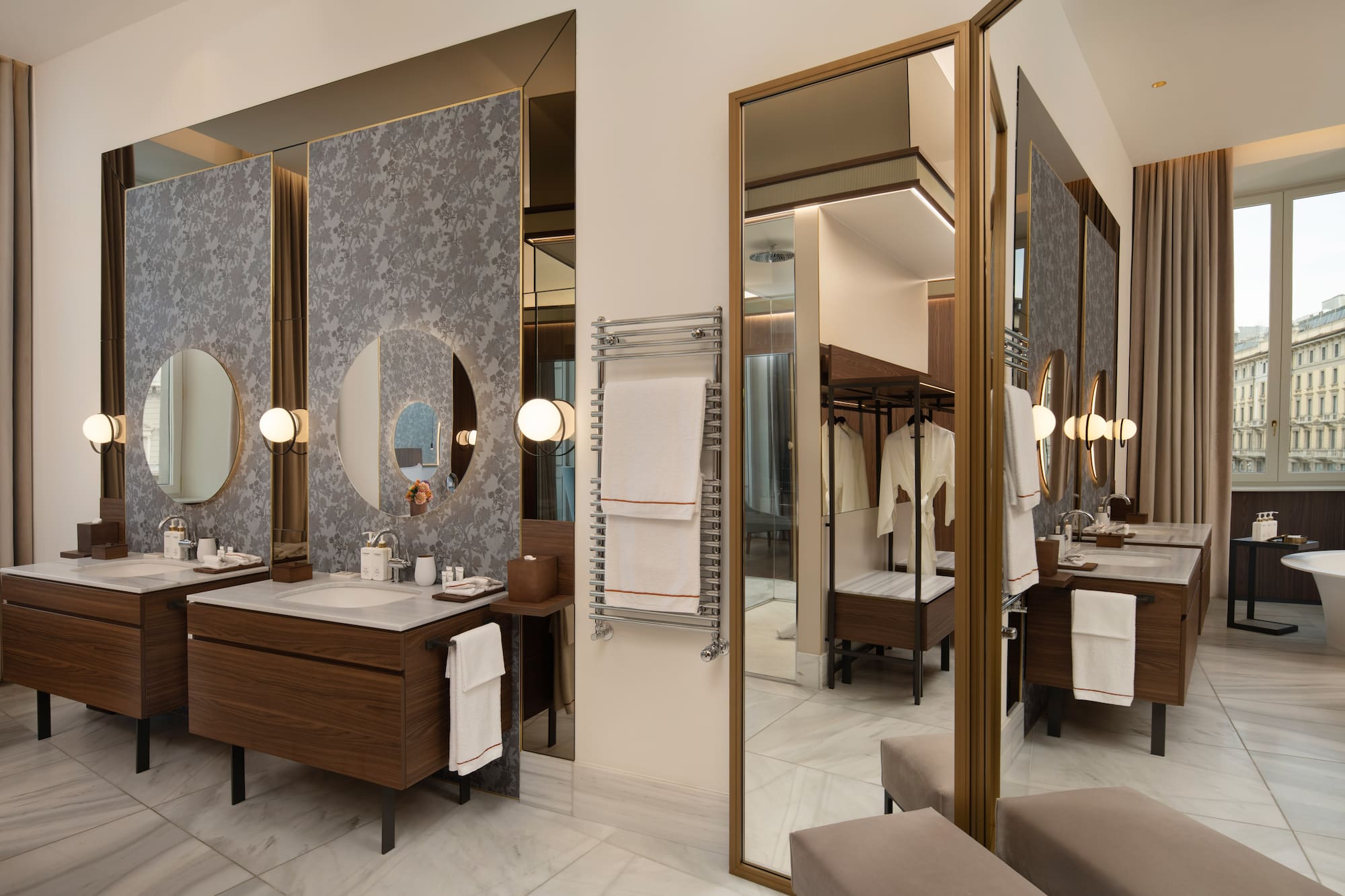 Luxury hotel bathroom with double vanity, round mirrors, marble, towel warmer.