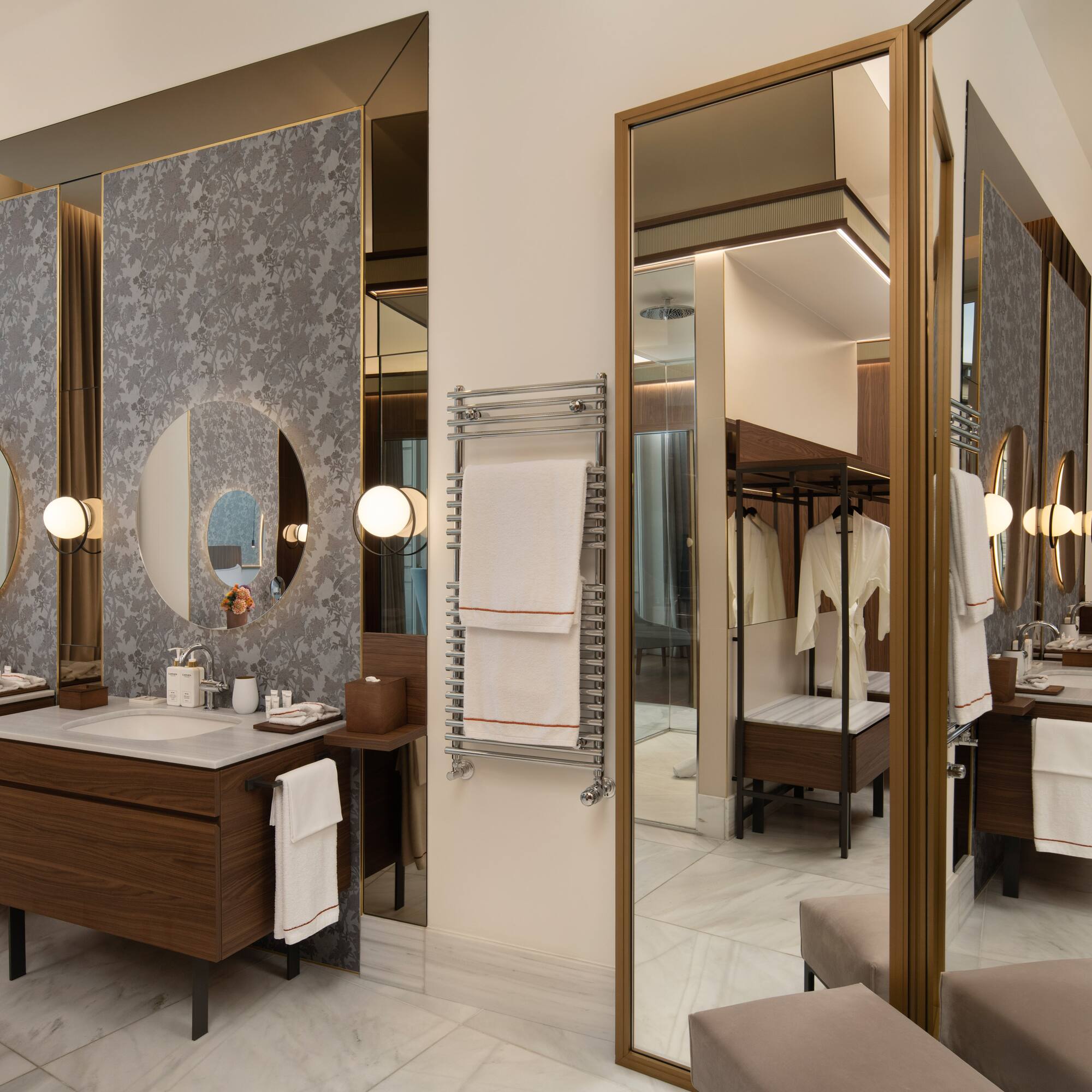 Luxury hotel bathroom with double vanity, round mirrors, marble, towel warmer.