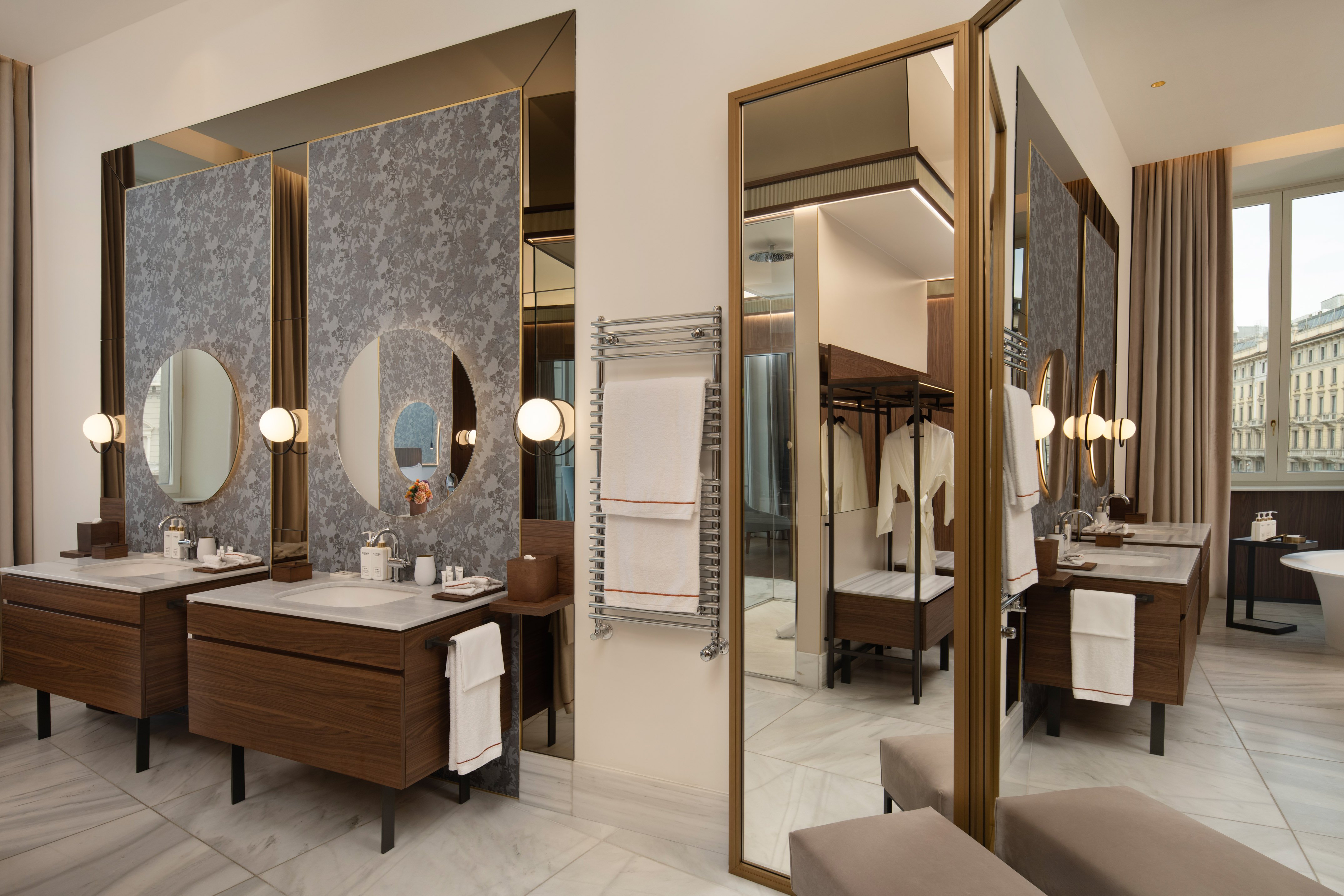 Luxury hotel bathroom with double vanity, round mirrors, marble, towel warmer.