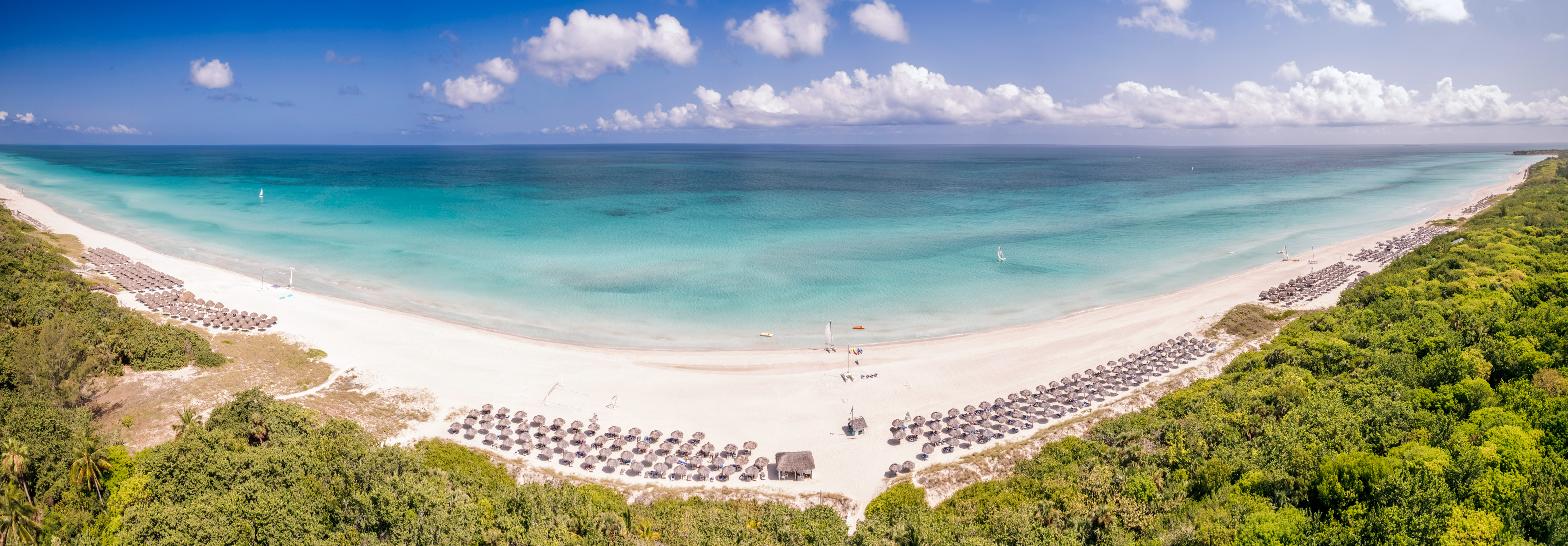 a beach with umbrellas and a body of water