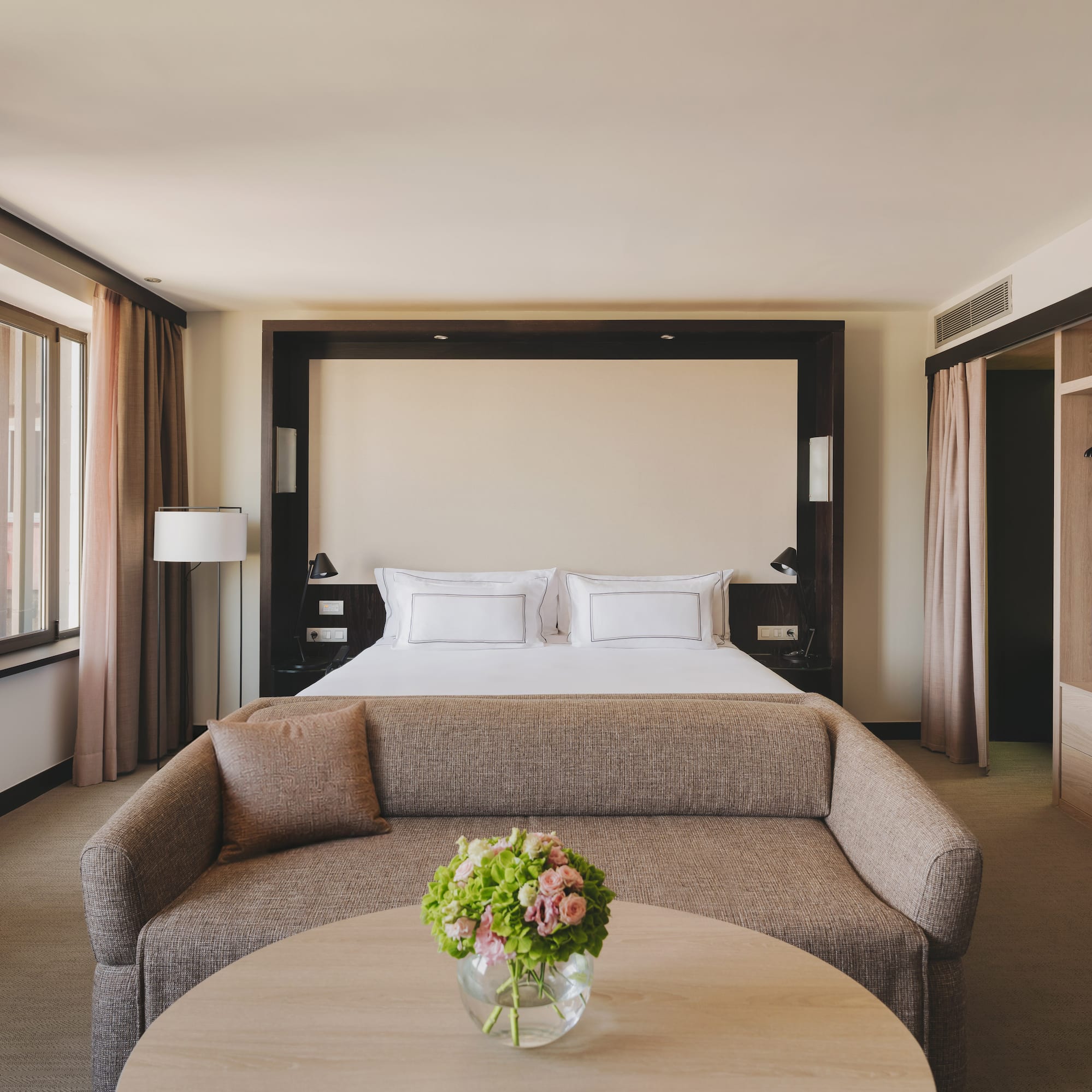 Habitación de hotel de lujo con cama king, sofá, mesa y armario empotrado.