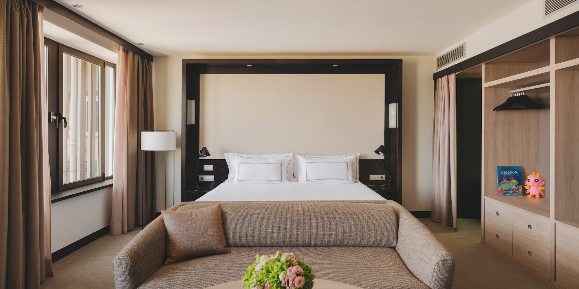 Habitación de hotel de lujo con cama king, sofá, mesa y armario empotrado.