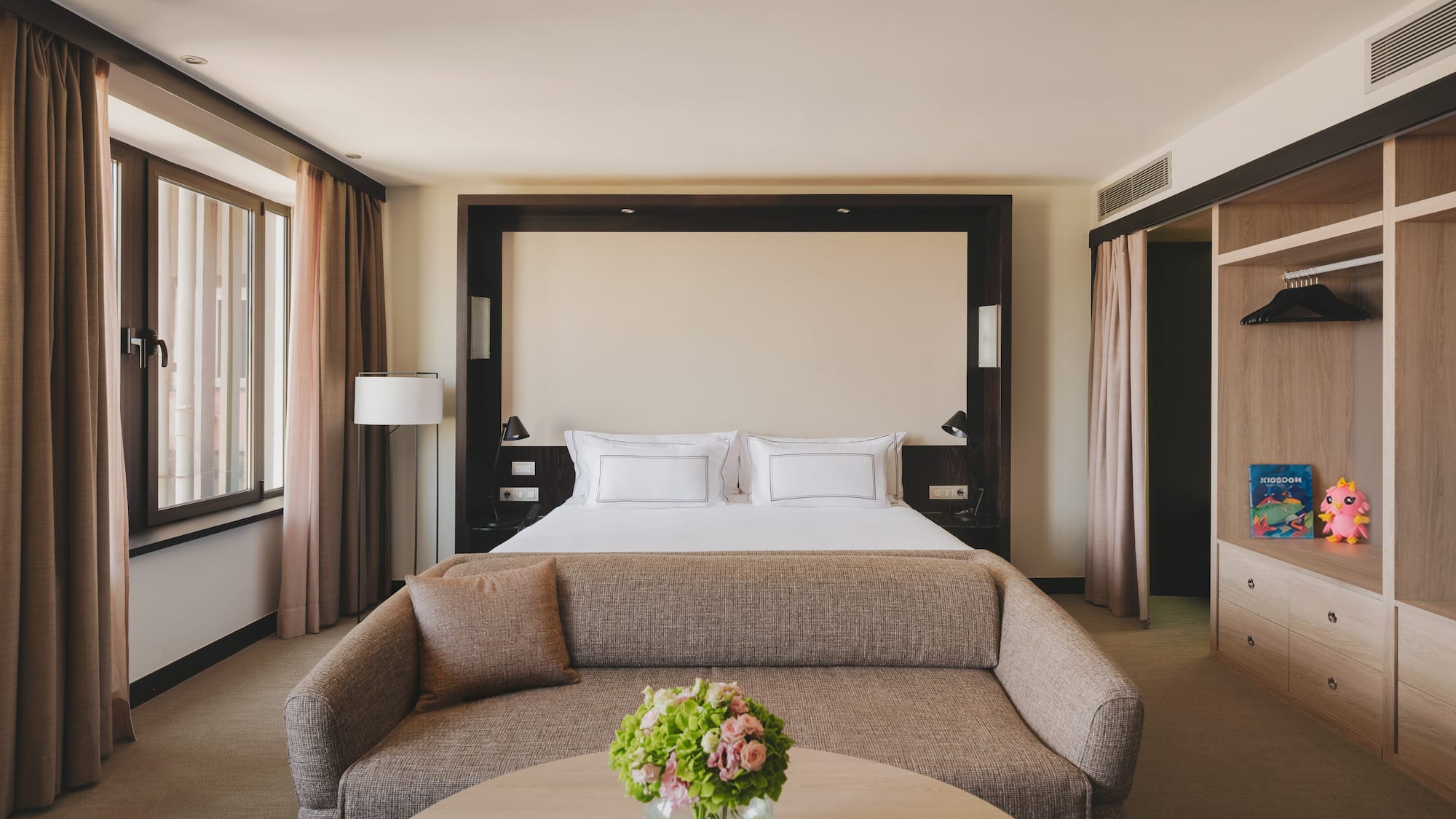 Habitación de hotel de lujo con cama king, sofá, mesa y armario empotrado.