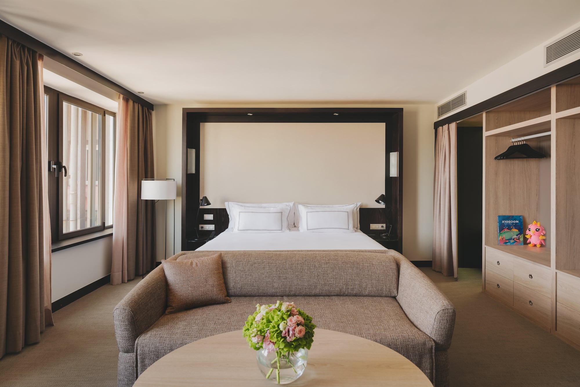 Habitación de hotel de lujo con cama king, sofá, mesa y armario empotrado.