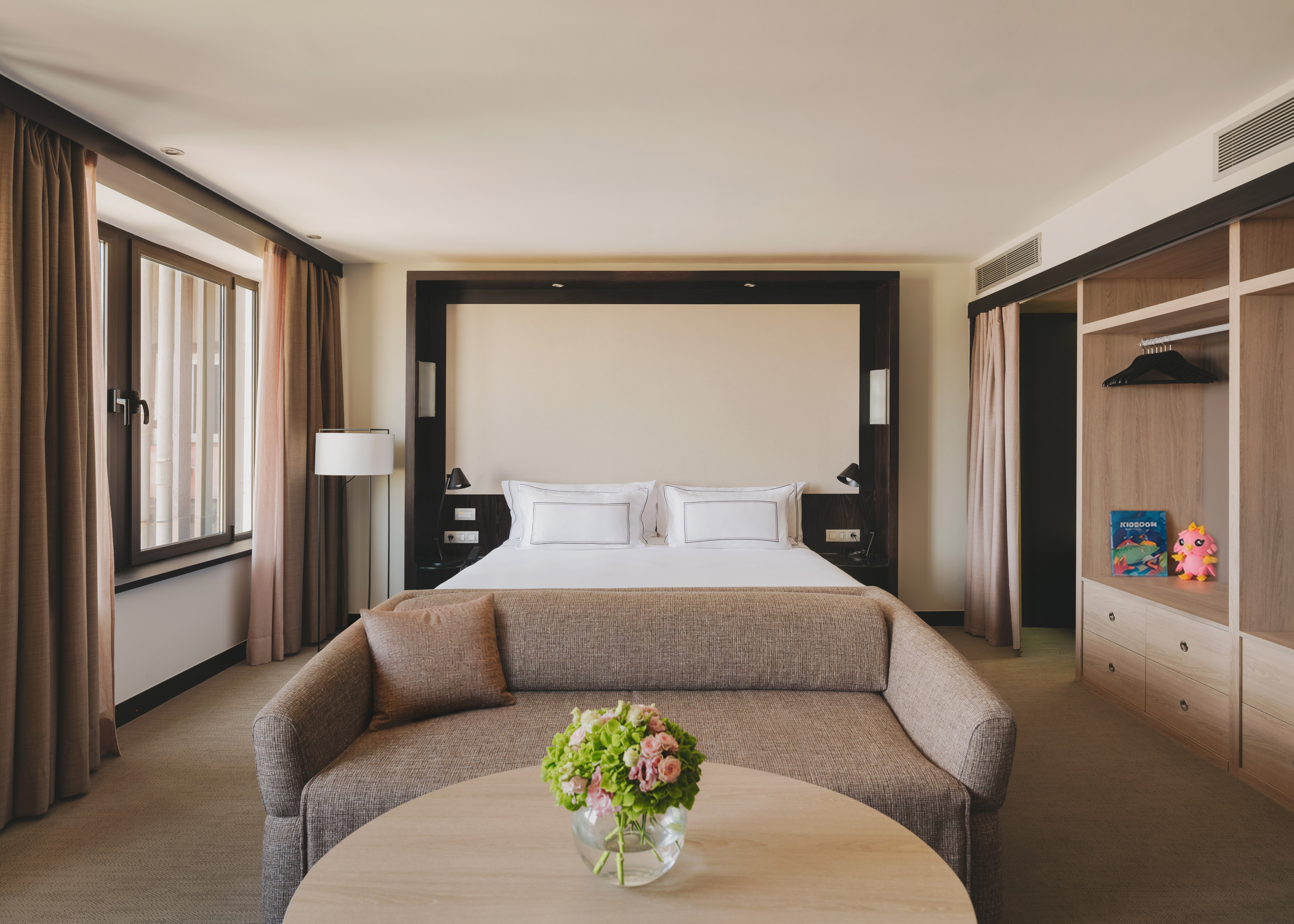 Habitación de hotel de lujo con cama king, sofá, mesa y armario empotrado.