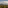 Volcano landscape: misty peak, green hills, valley town with jacaranda trees.