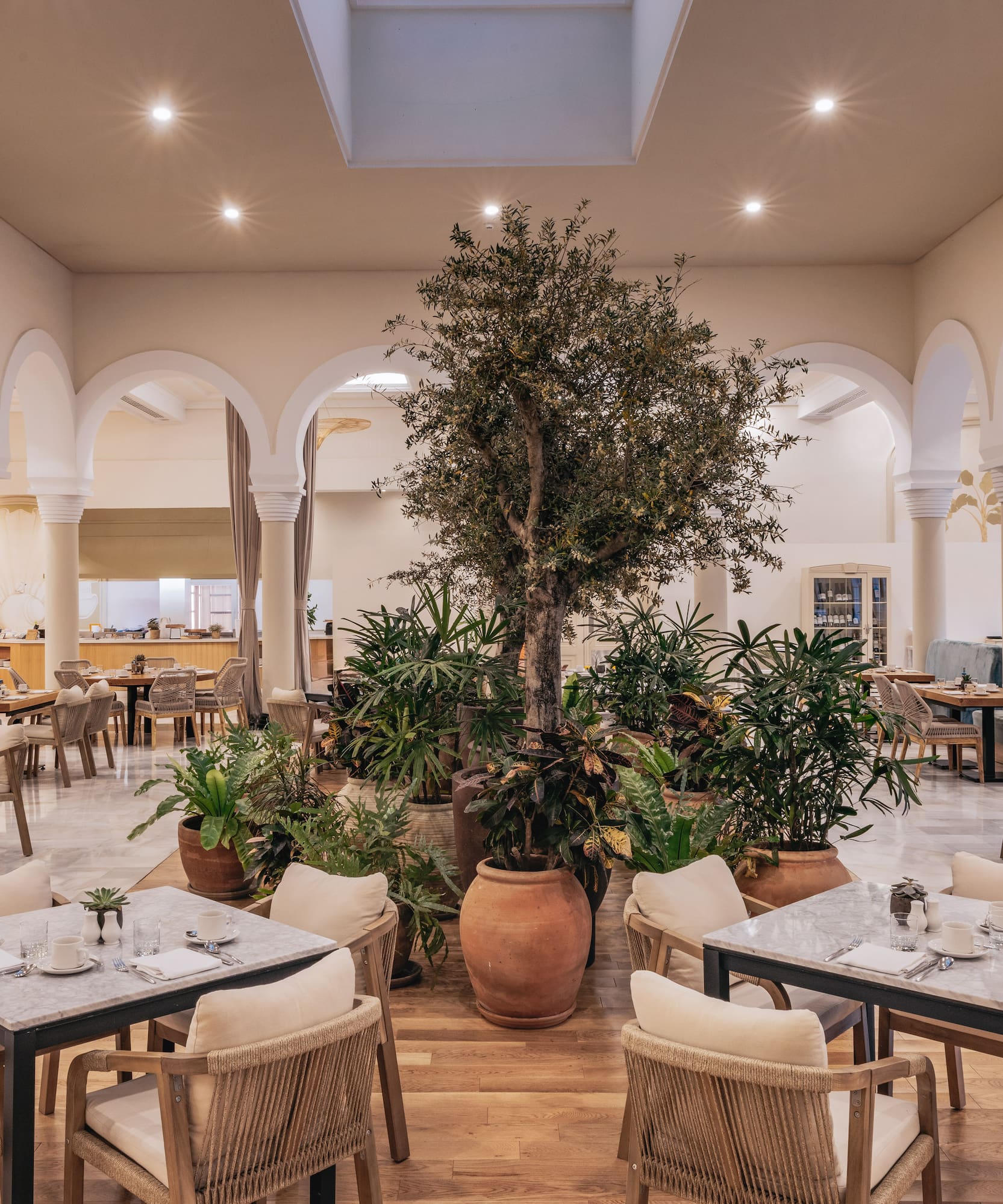 Elegant resort restaurant with arches, central tree, and dining tables.