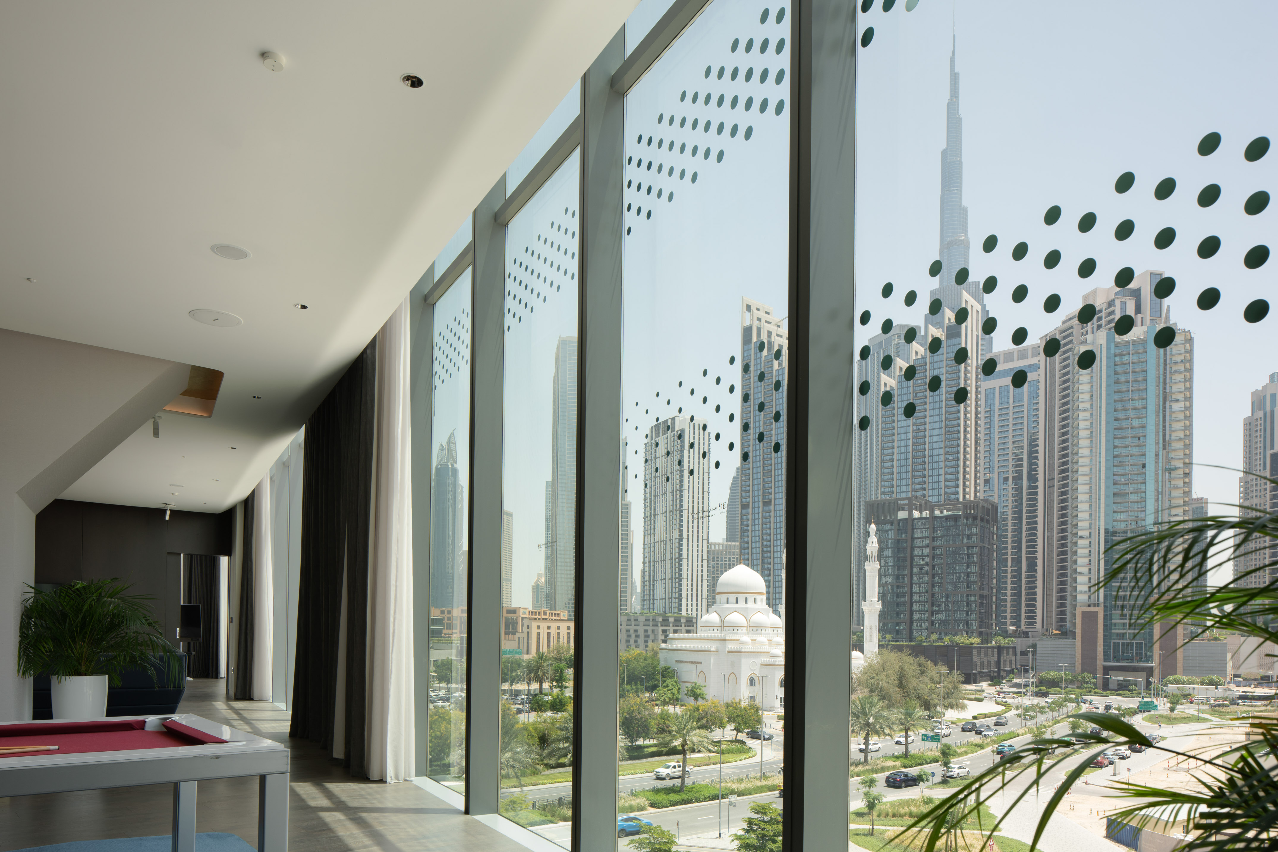 Modern lounge with pool table, Dubai cityscape view, Burj Khalifa and mosque.