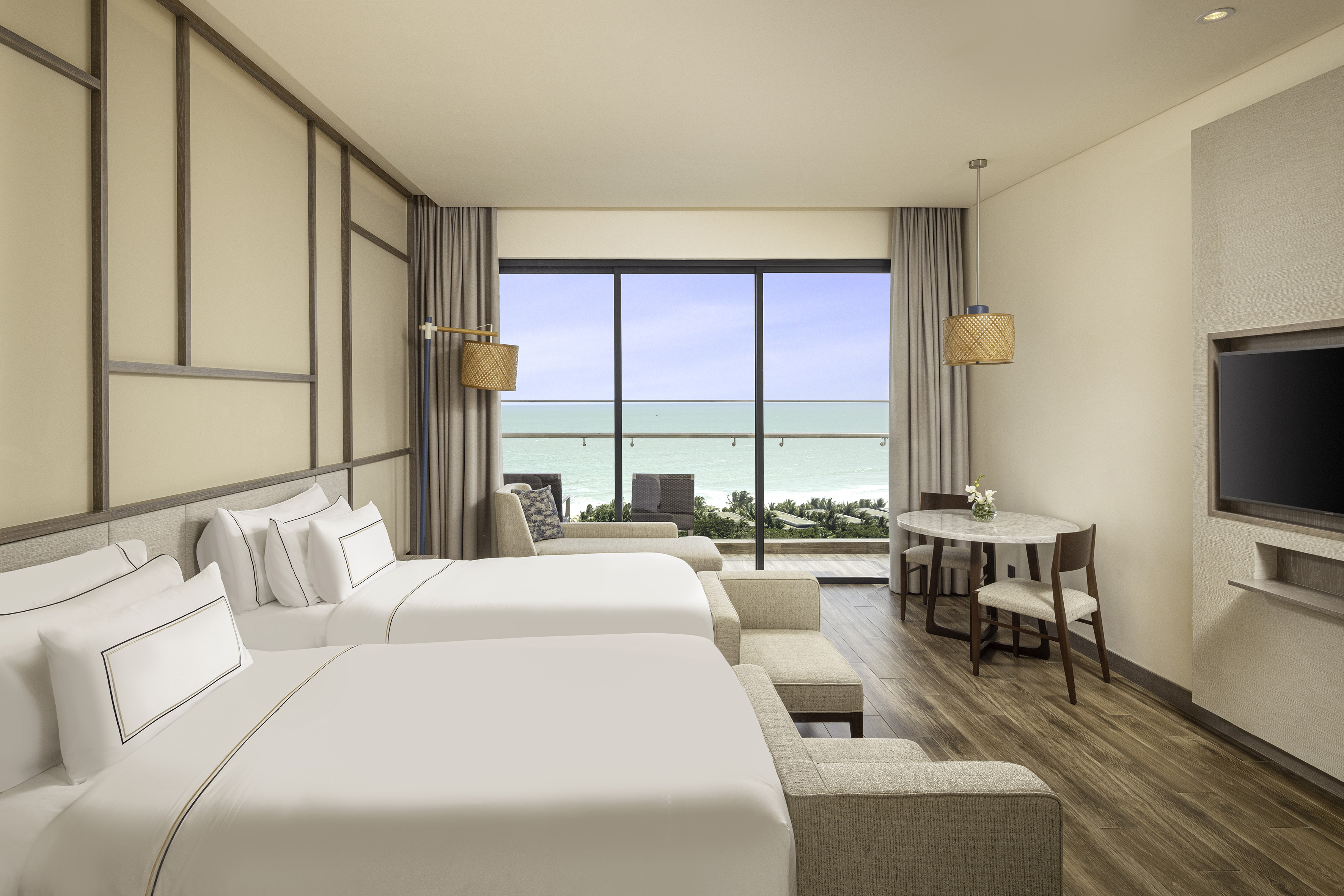 Modern hotel room with two beds, ocean view balcony.