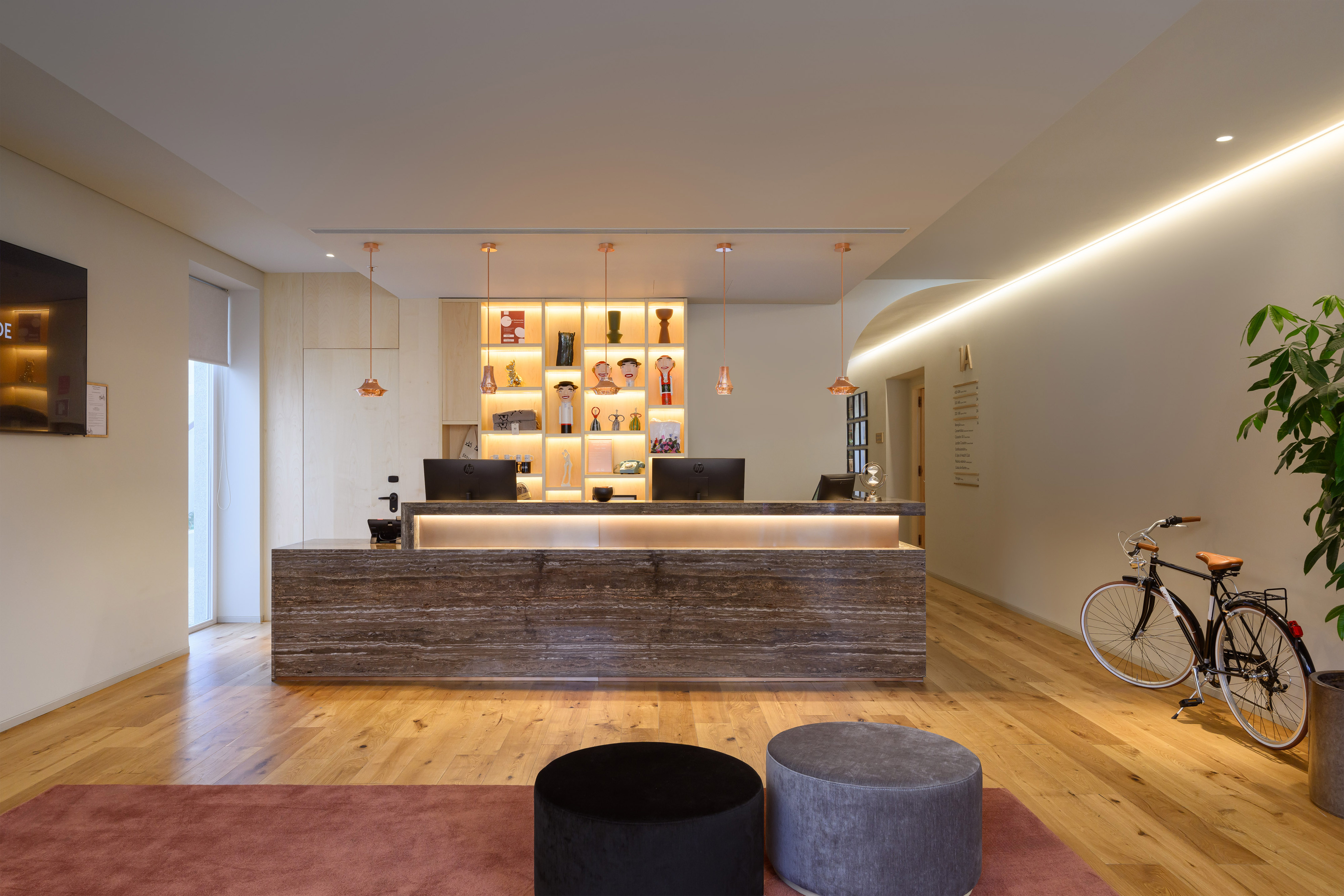 Modern hotel reception with glowing front desk, wood floor, and unique bicycle.