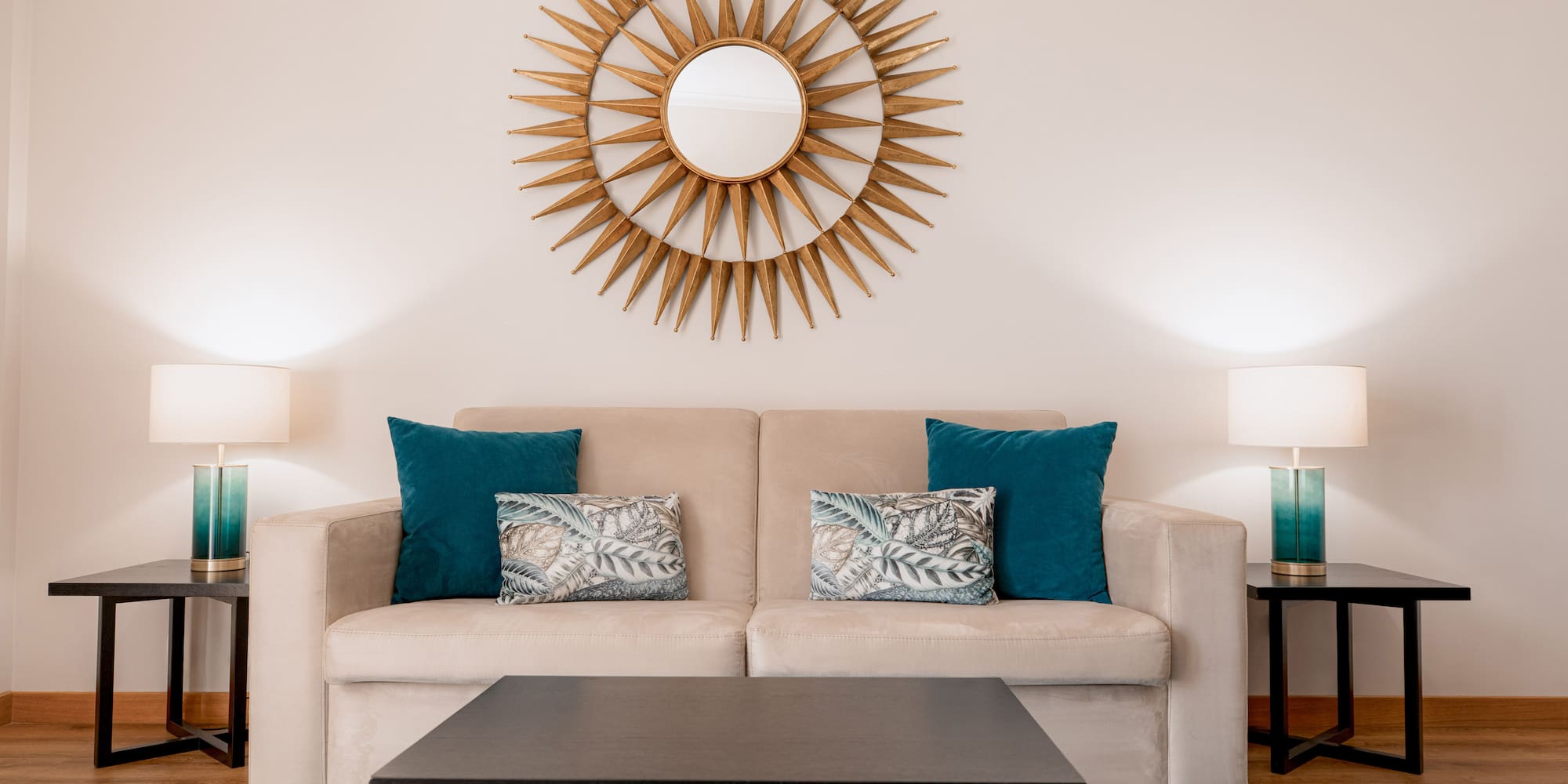 a couch with pillows and a coffee table in front of a mirror