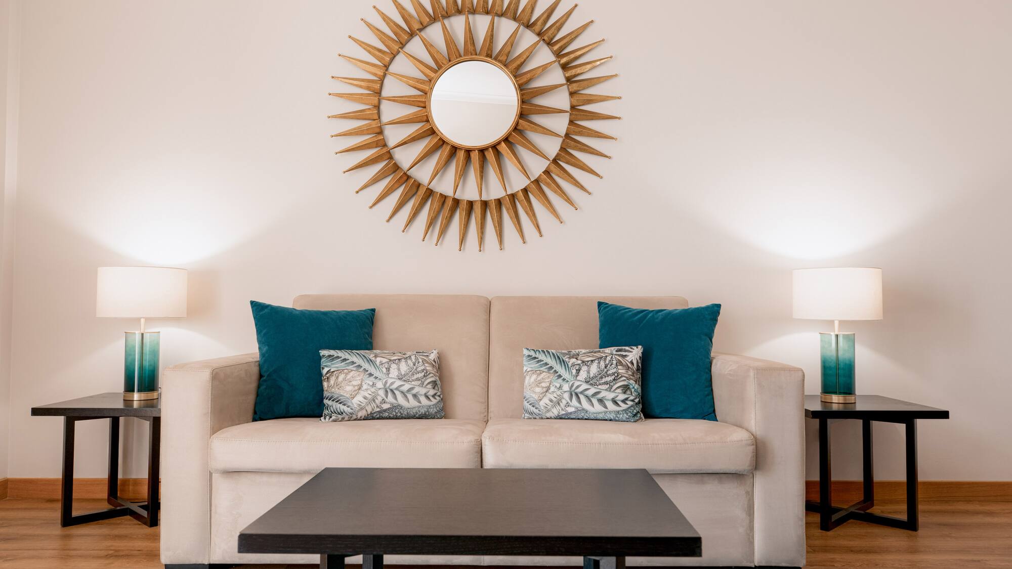 a couch with pillows and a coffee table in front of a mirror