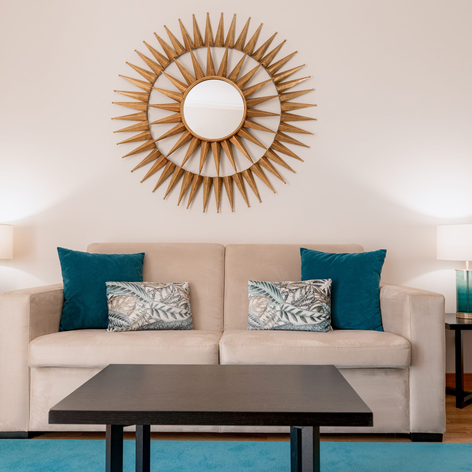 a couch with pillows and a coffee table in front of a mirror