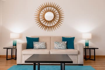 a couch with pillows and a coffee table in front of a mirror