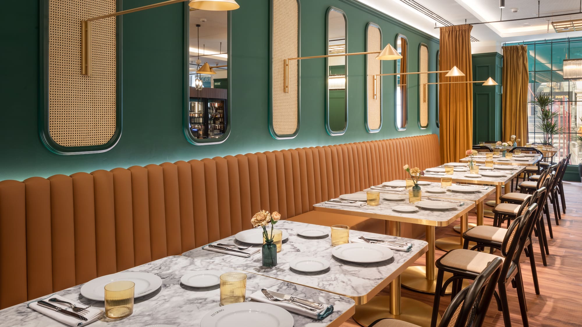 a long table with white plates and gold lamps