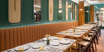 a long table with white plates and gold lamps