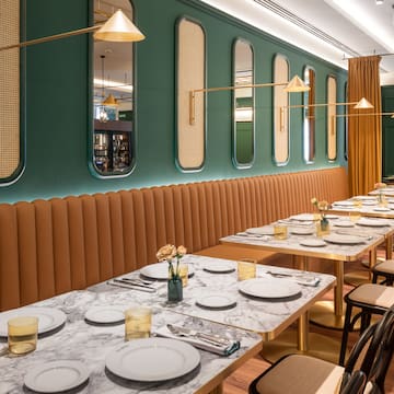 a long table with white plates and gold lamps