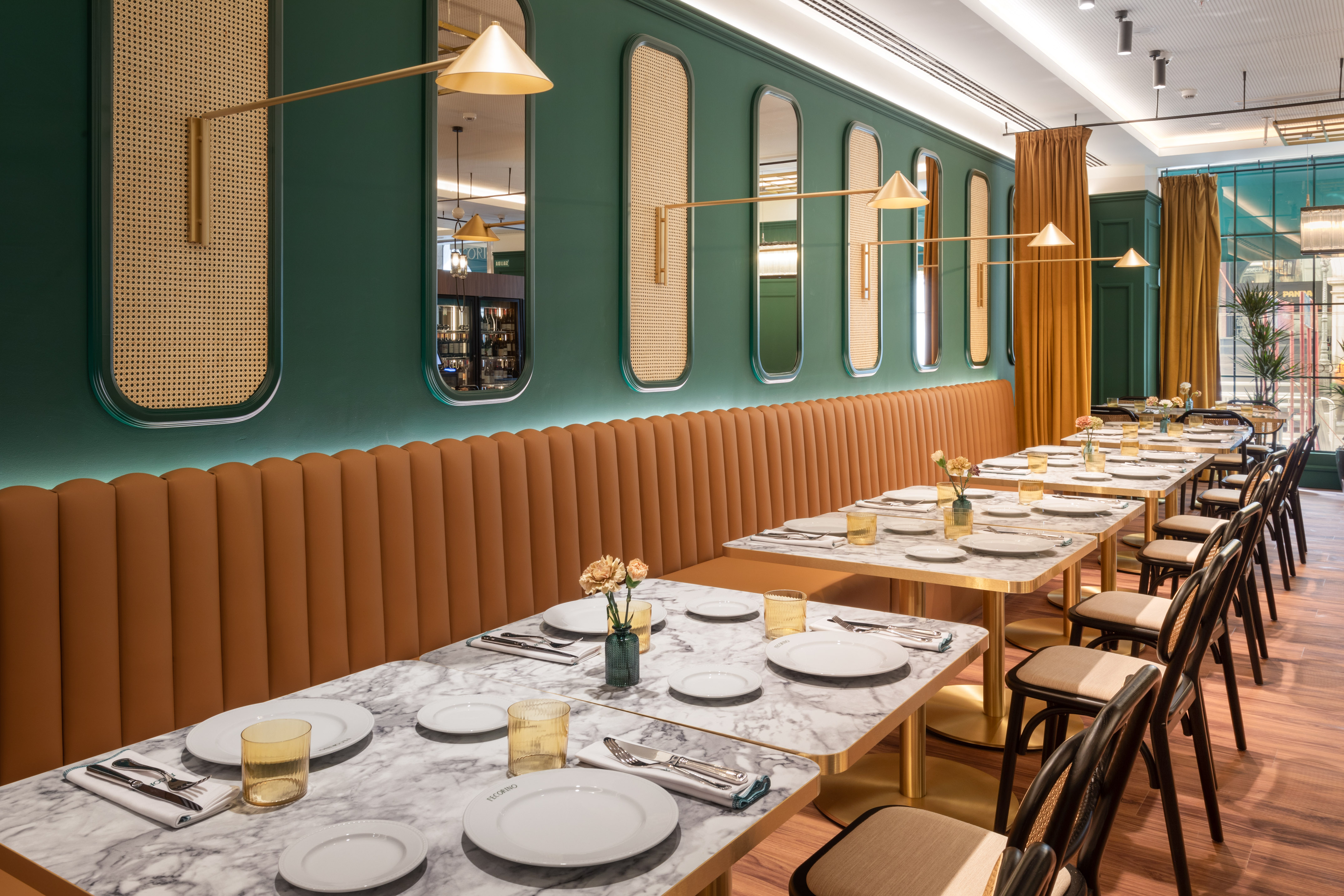 Elegant restaurant: green walls, tan banquette, marble tables, gold accents.
