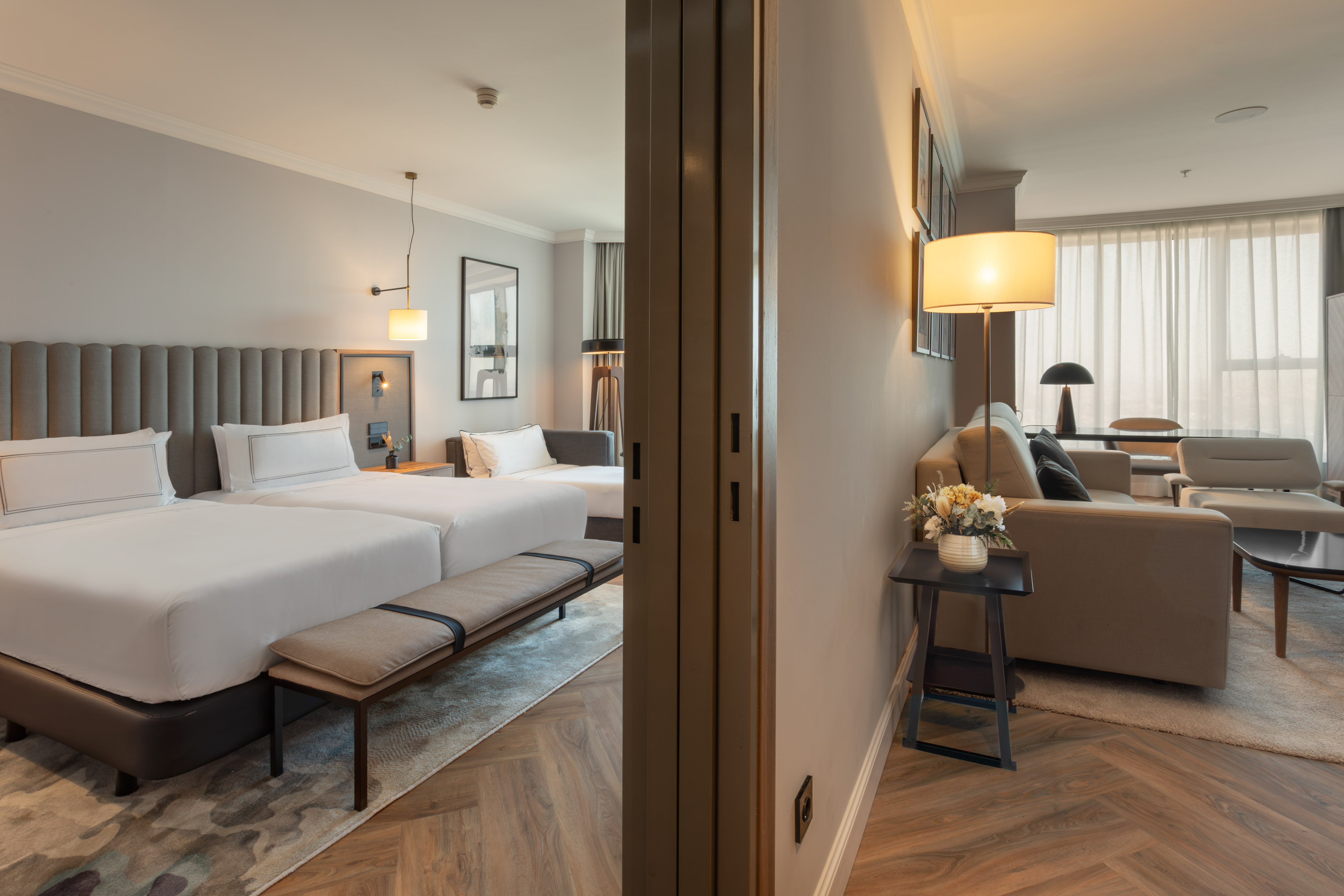 Suite de hotel moderna: dormitorio con dos camas, y sala de estar. Diseño elegante.