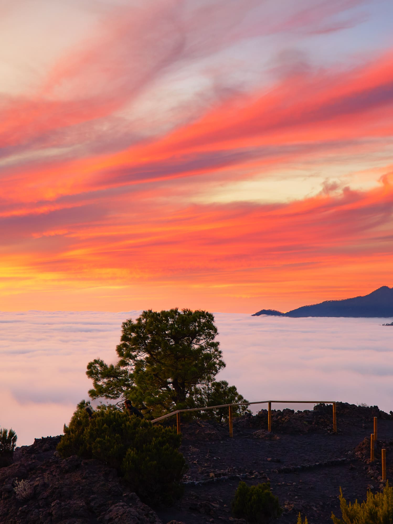 a person standing on a hill overlooking clouds and mountains