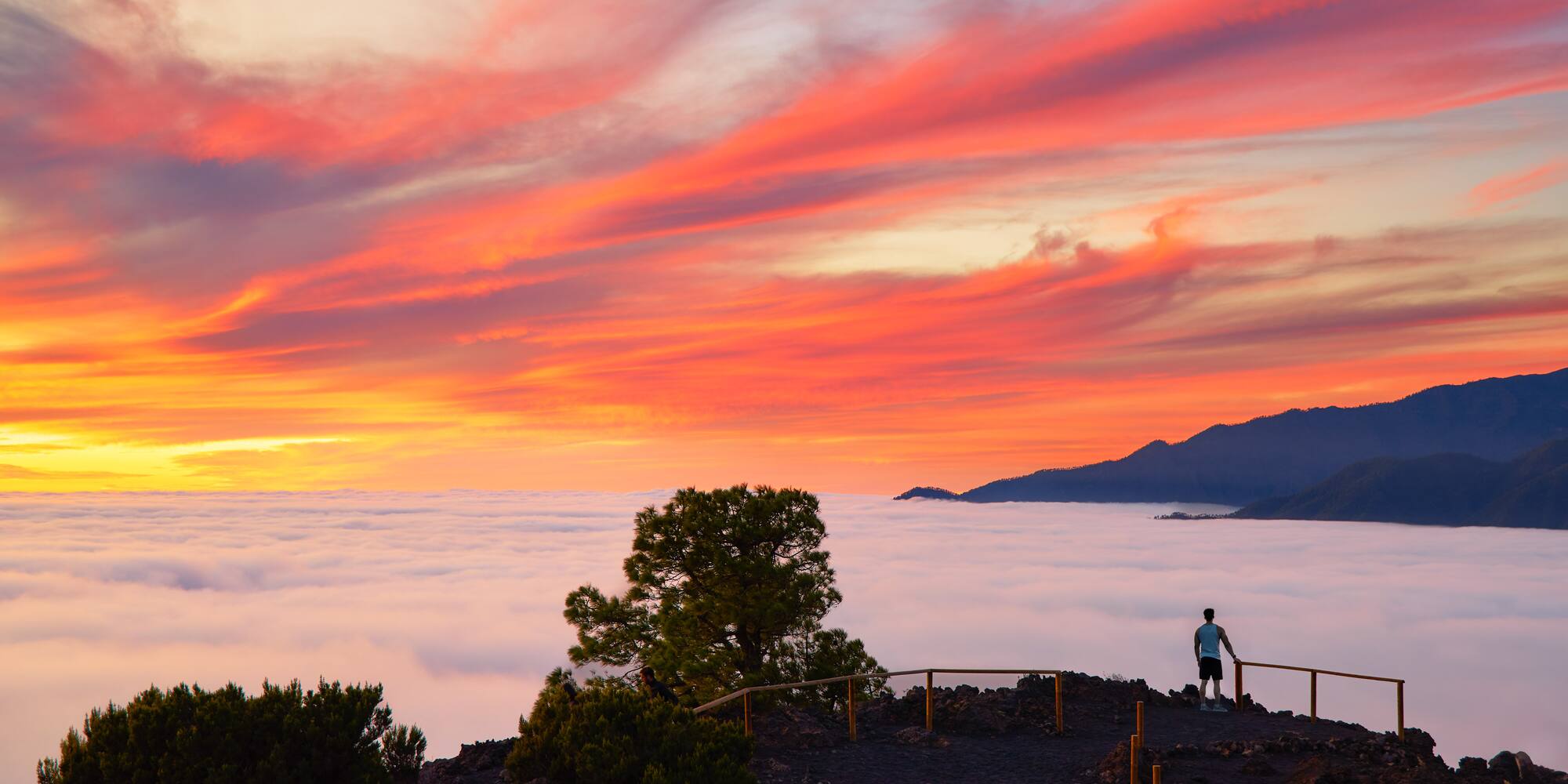 a person standing on a hill overlooking clouds and mountains