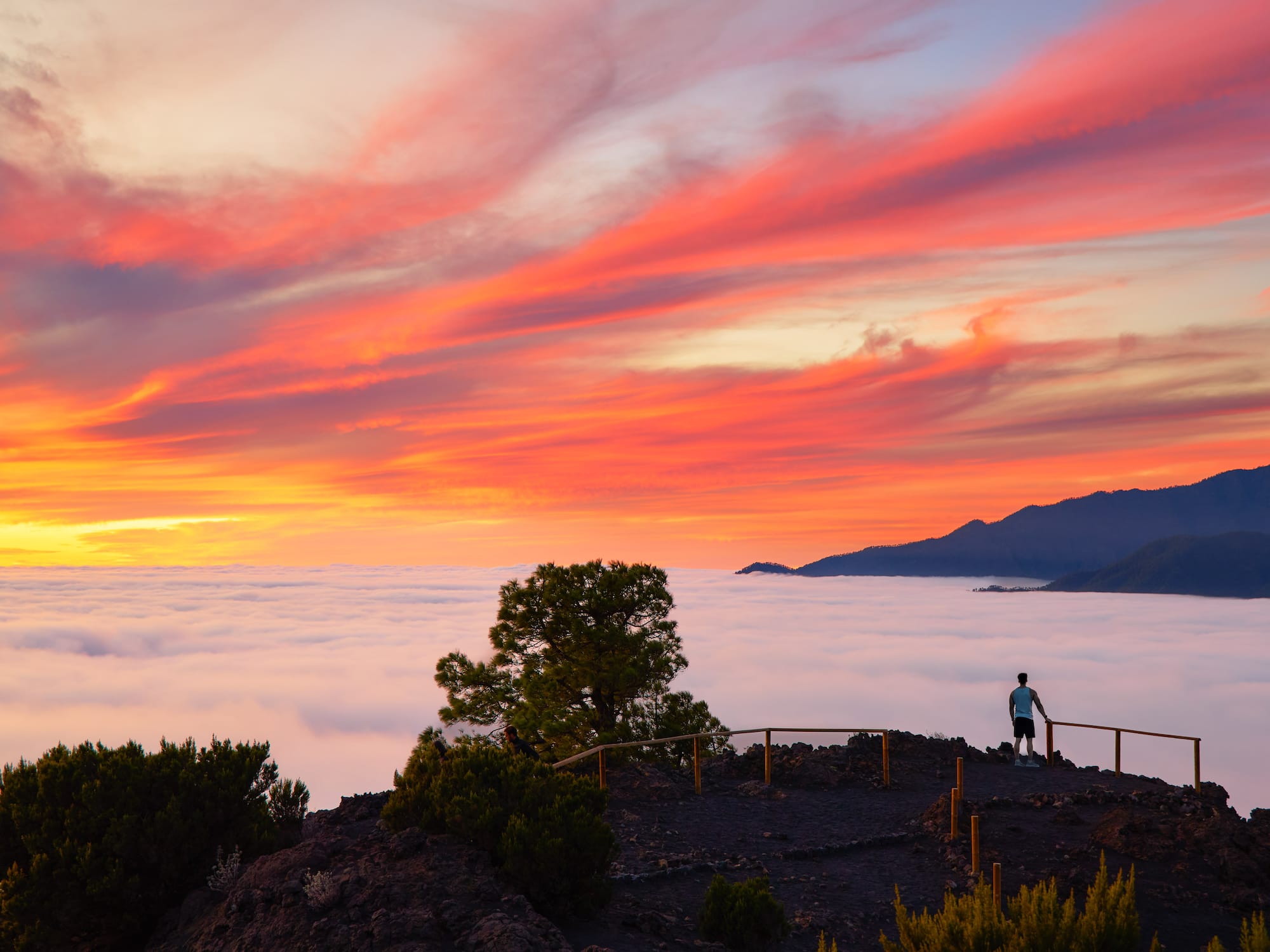 a person standing on a hill overlooking clouds and mountains