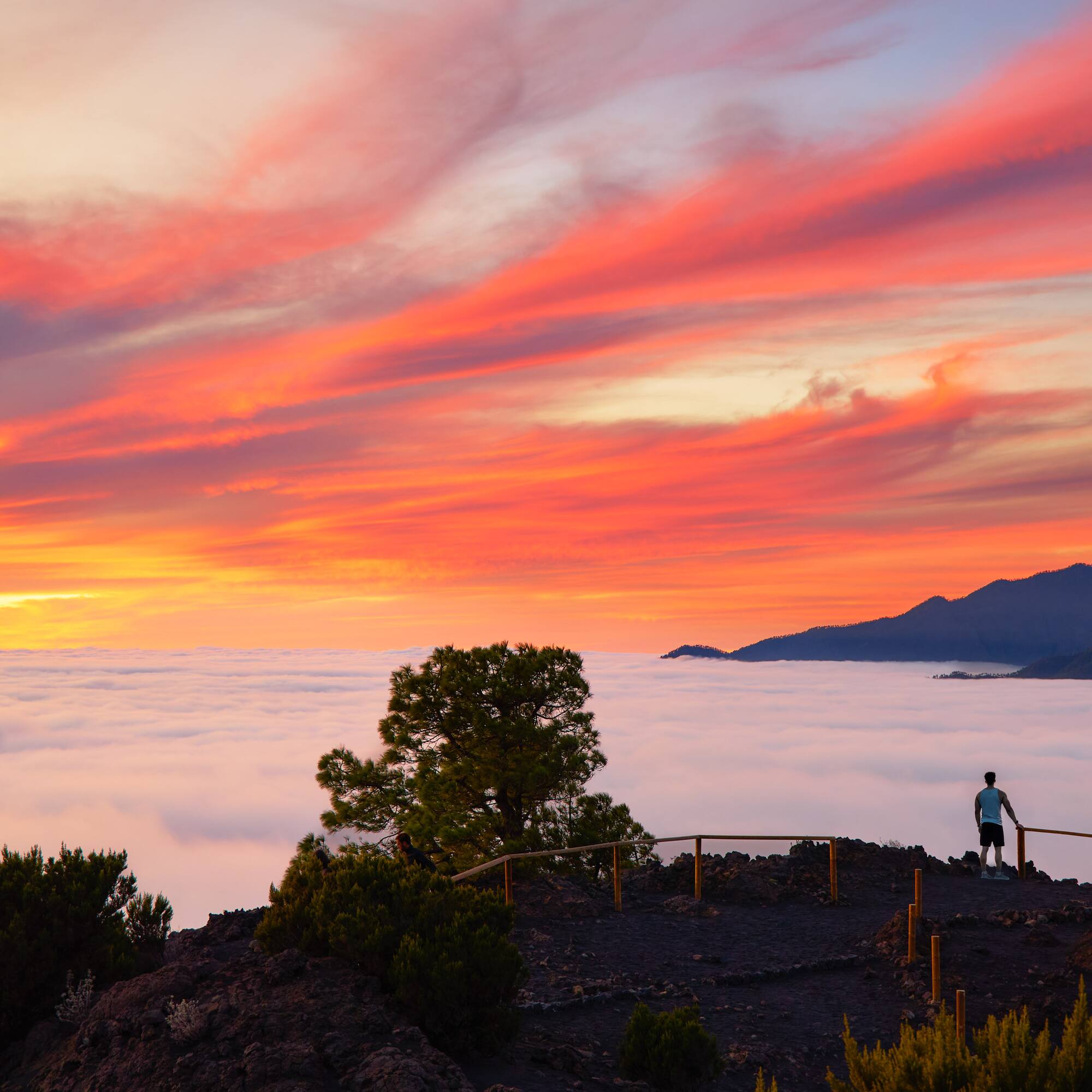 a person standing on a hill overlooking clouds and mountains