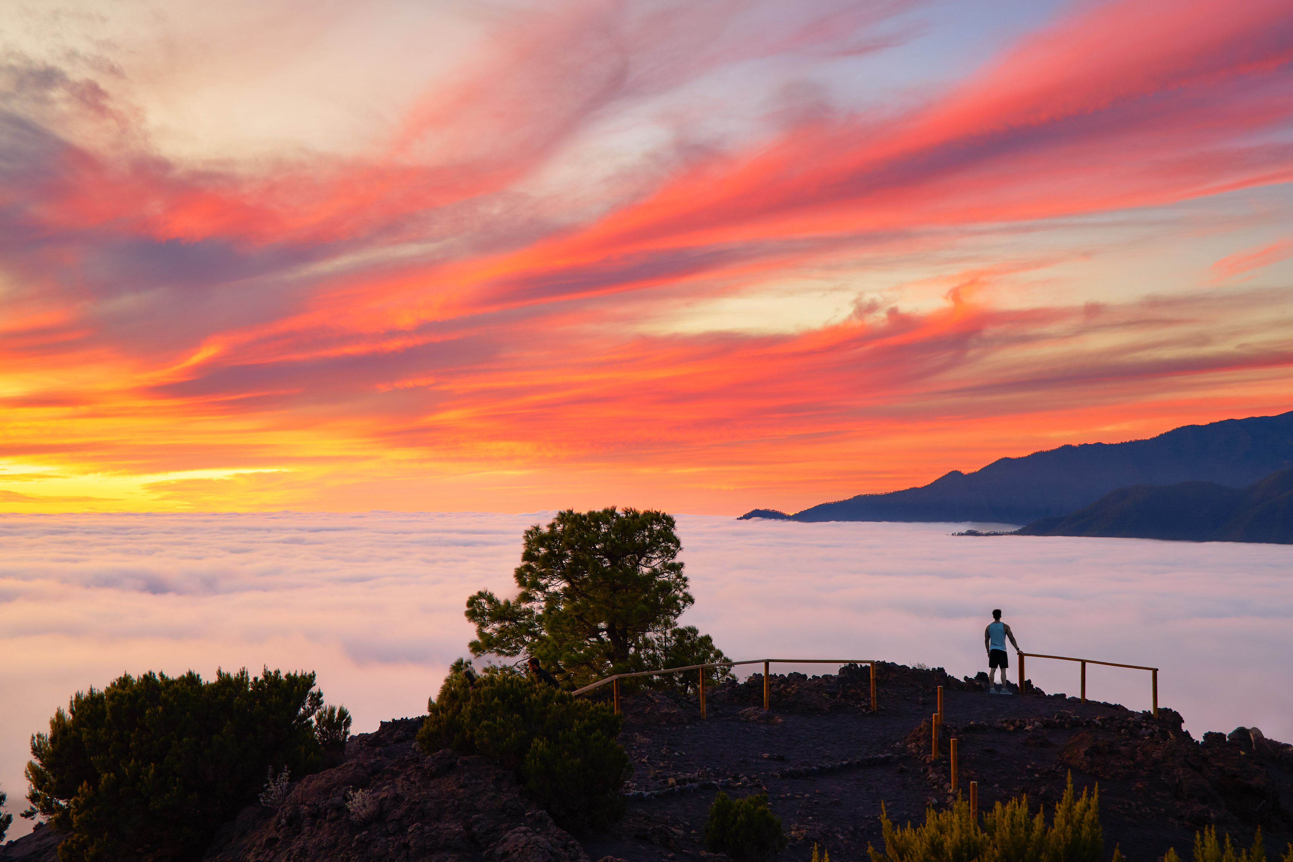 a person standing on a hill overlooking clouds and mountains