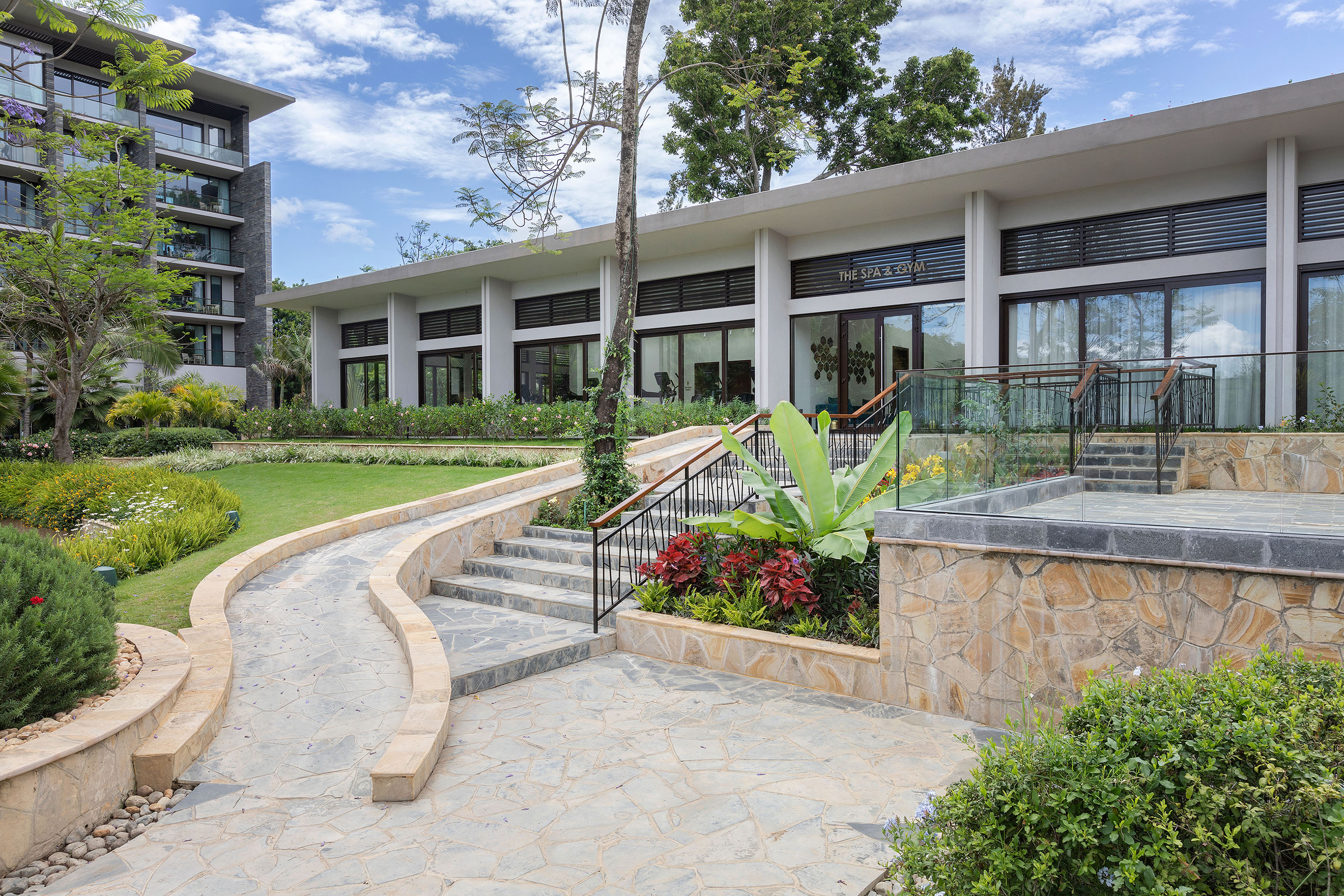Tropical resort spa & gym, stone pathways, lush gardens, modern hotel.