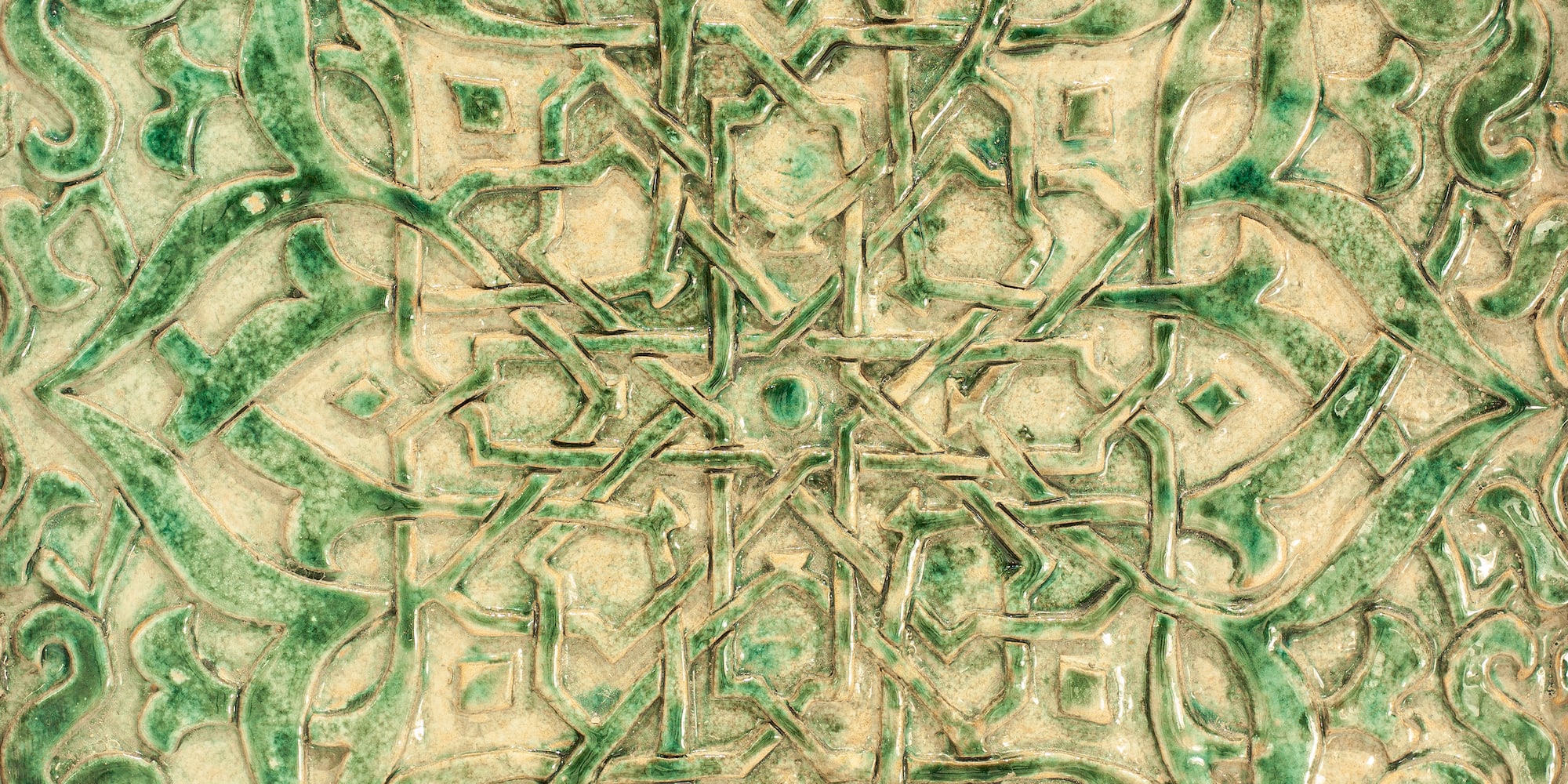 Azulejo cerámico verde con patrón geométrico islámico en relieve.