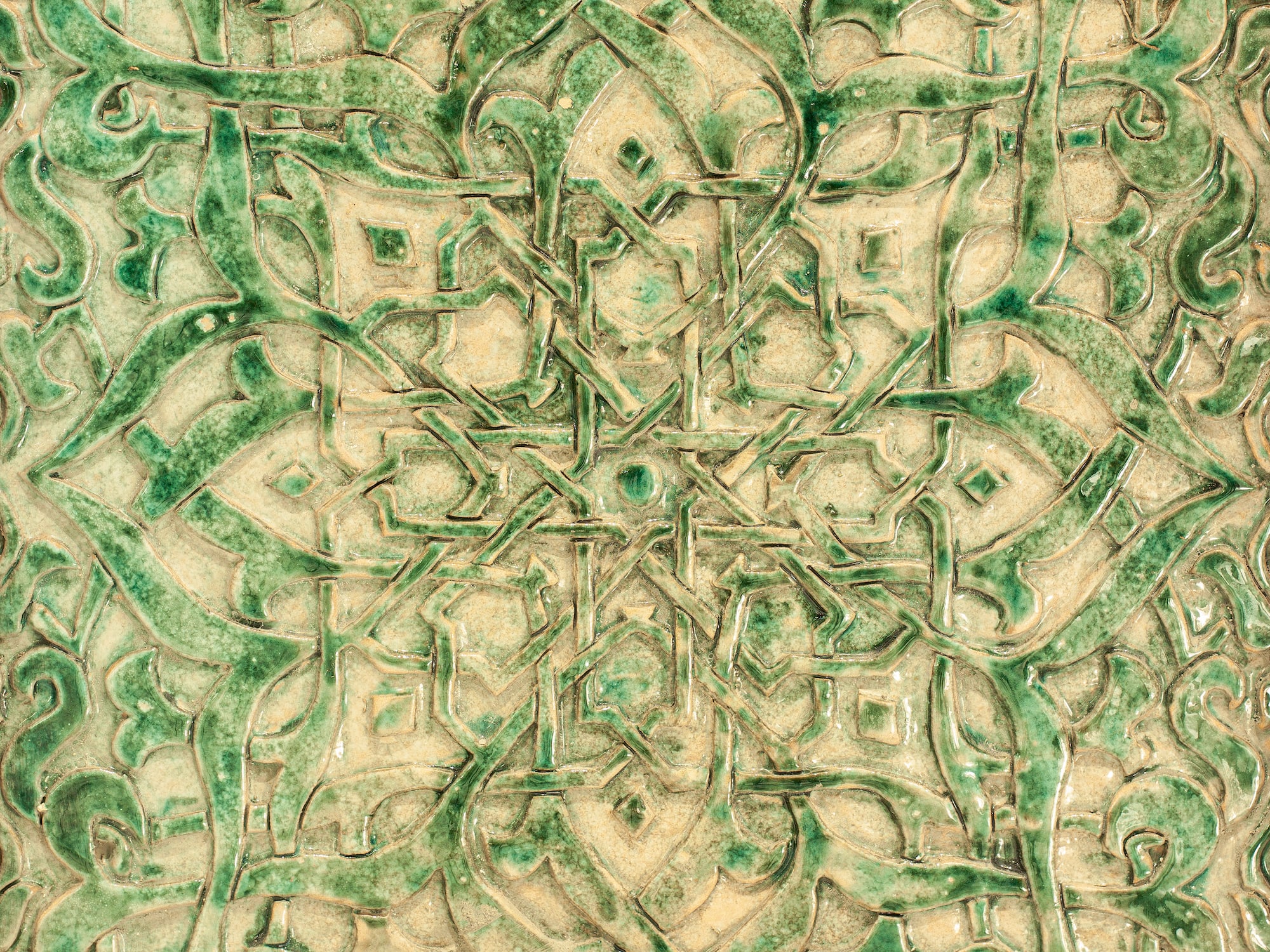 Azulejo cerámico verde con patrón geométrico islámico en relieve.