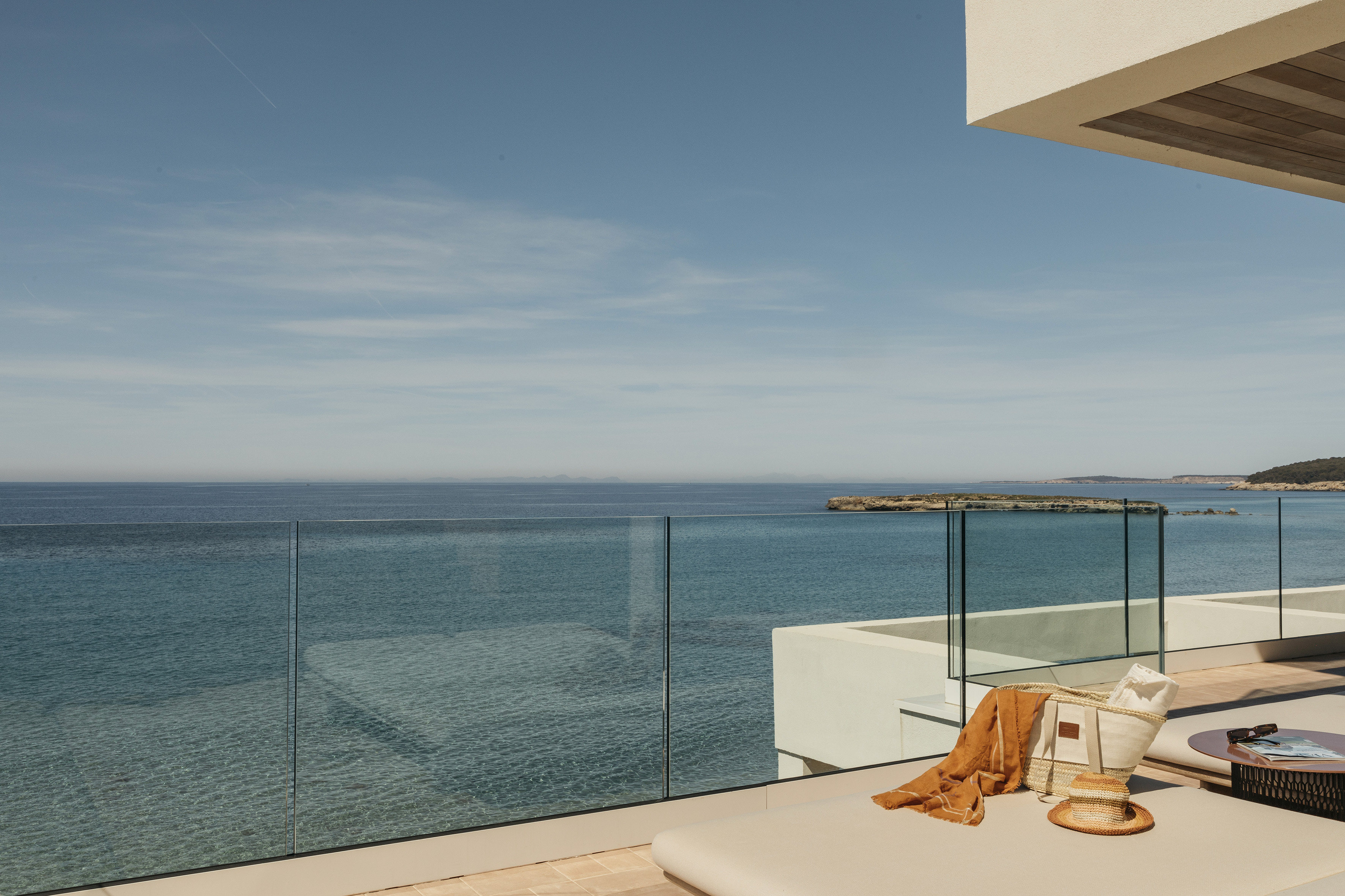 Luxury balcony with daybed overlooking clear blue sea and distant islands.