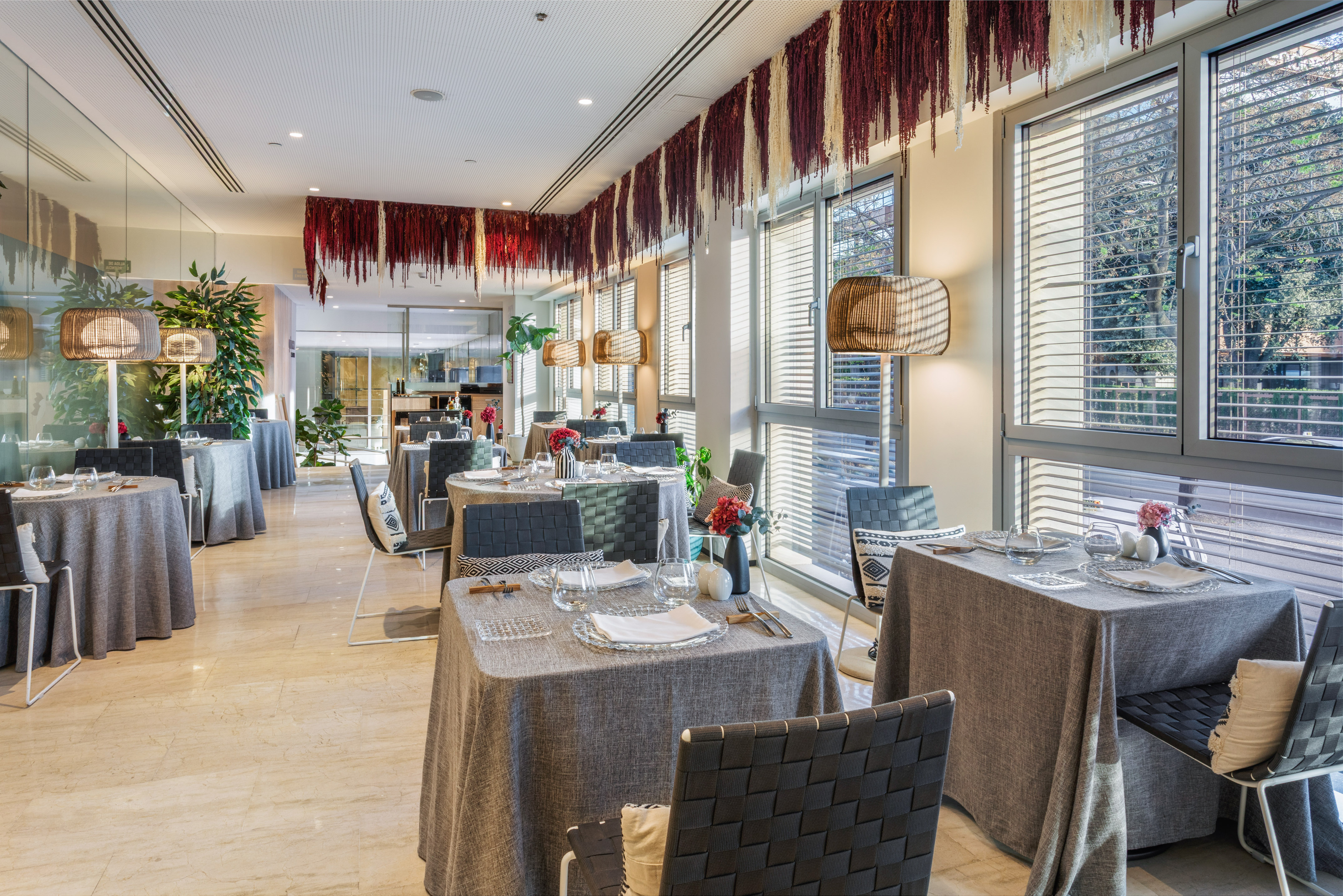 Modern restaurant dining room with set tables, natural light, and unique ceiling decor.