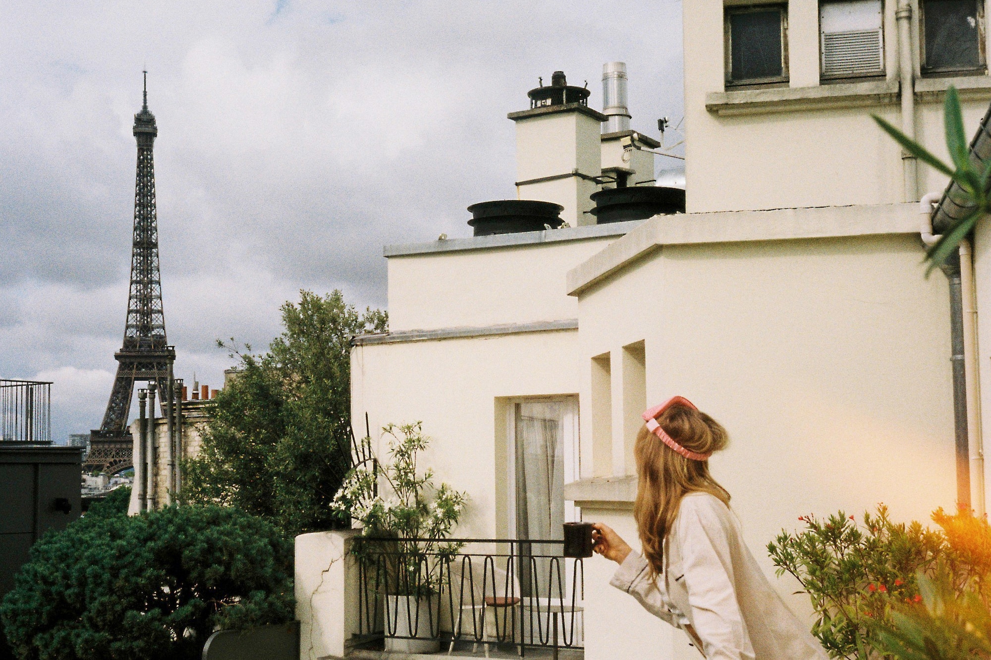 Mujer en balcón de París con taza, vista a la Torre Eiffel.