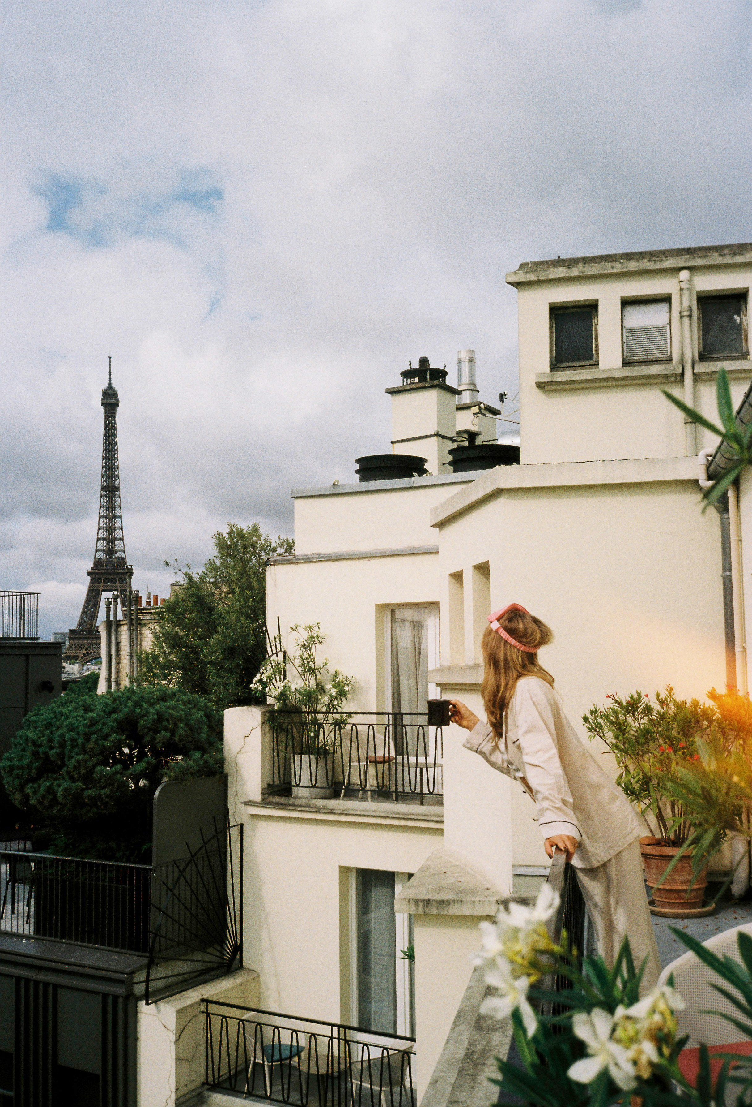 Mujer en balcón de París con taza, vista a la Torre Eiffel.