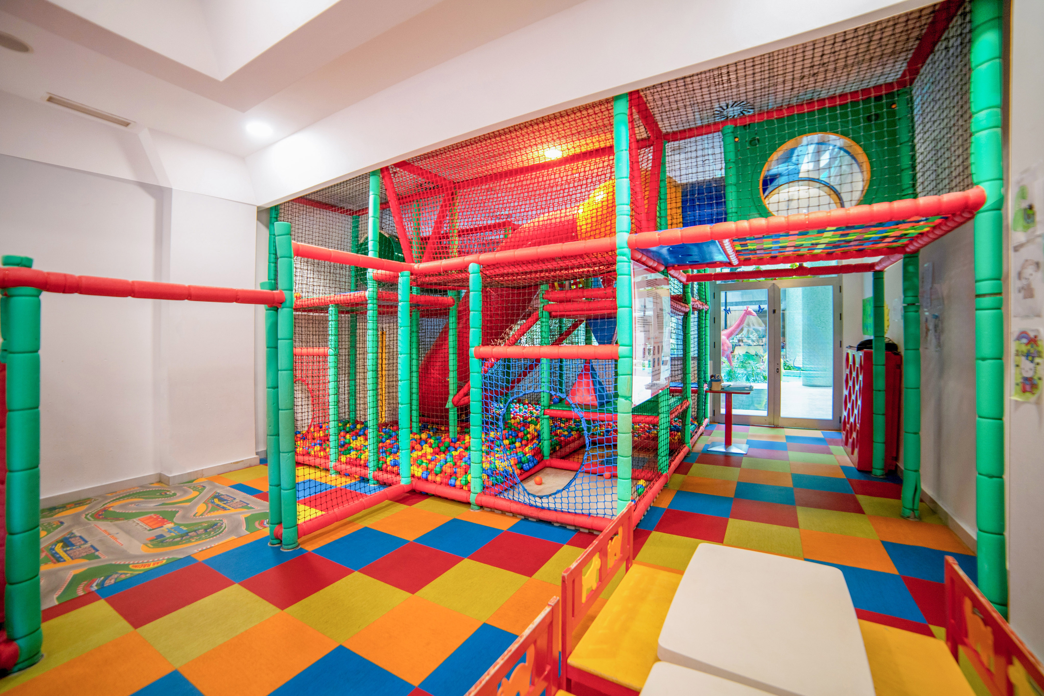 Colorful indoor soft play area with ball pit and checkered floor.
