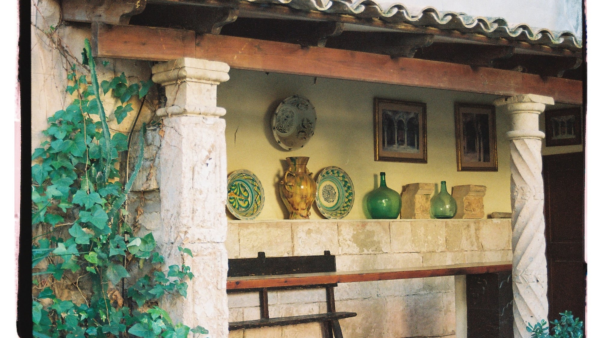 a stone wall with a shelf full of plates and vases