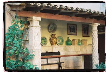 a stone wall with a shelf full of plates and vases