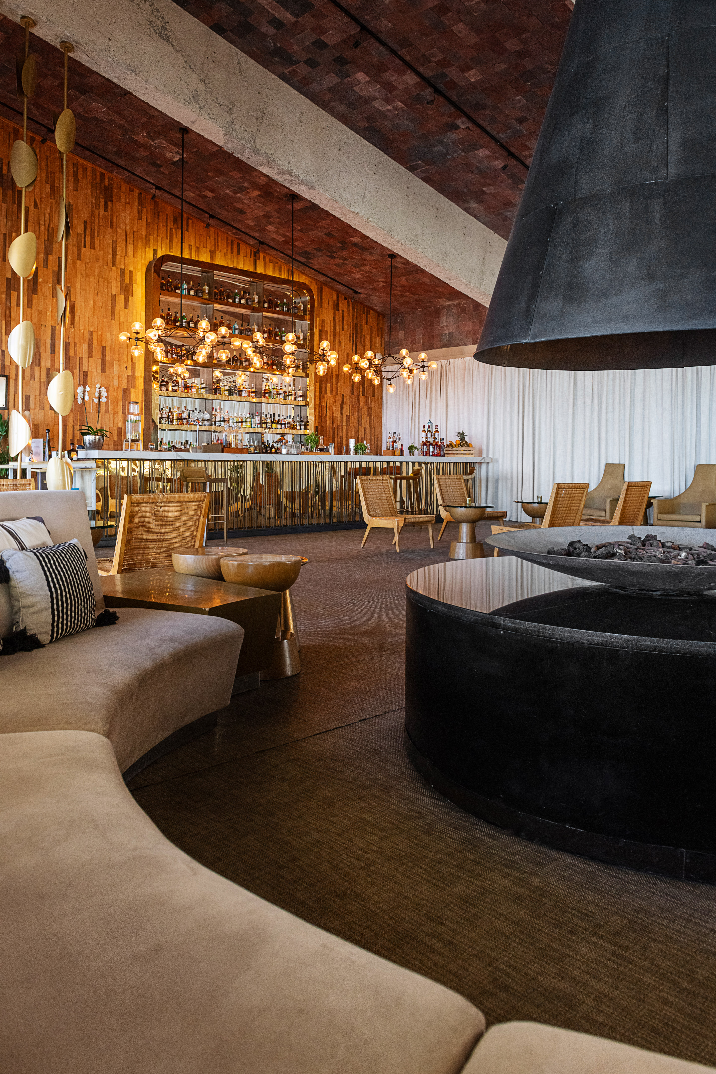 Modern bar lounge with golden counter, wood paneling, and unique fireplace.